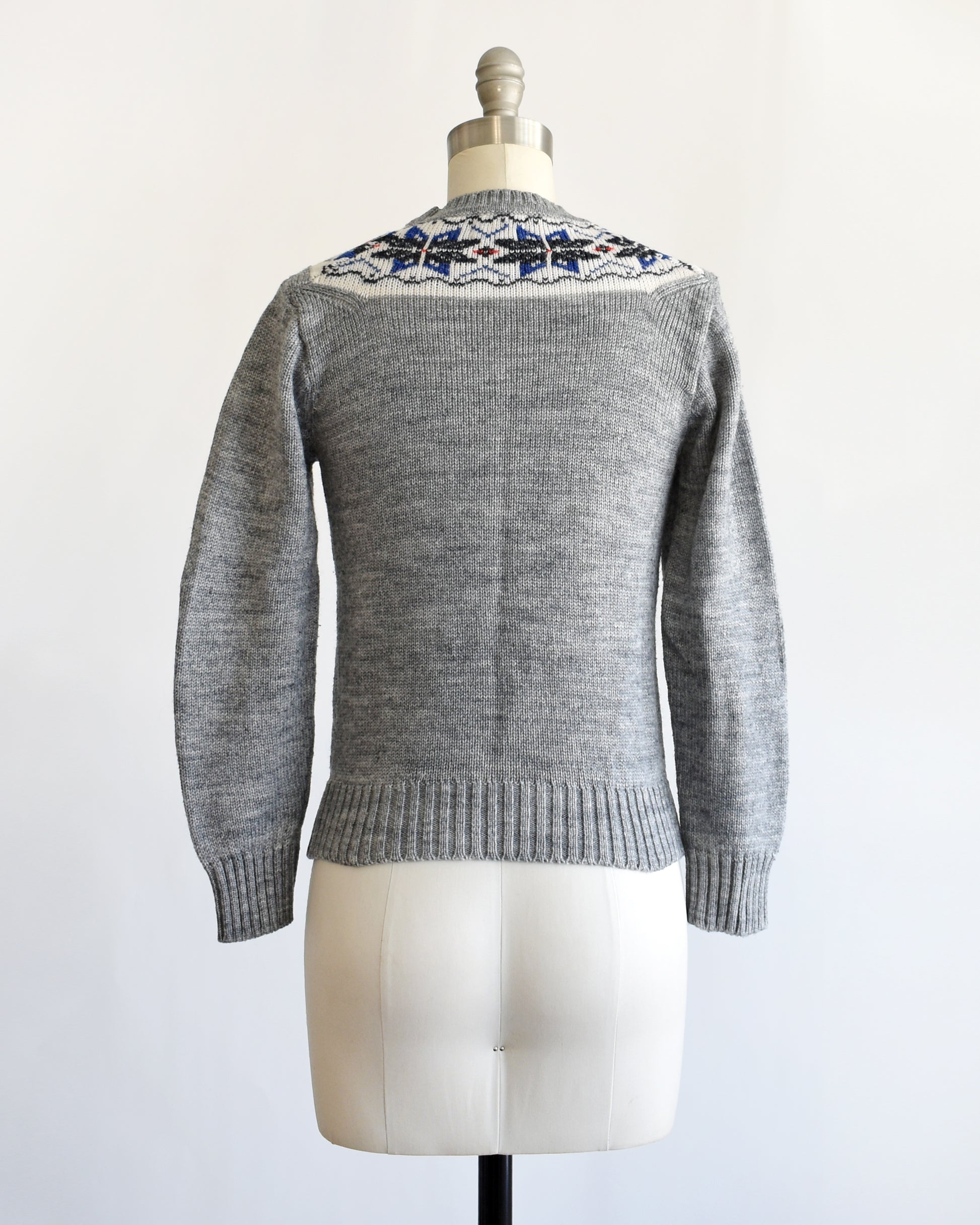 back view of a vintage 70s gray sweater with snowflake patterned neckline on a mannequin against a white background