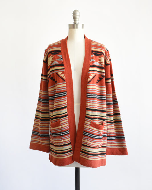 A vintage 1970s long-sleeve open-front cardigan with a Southwestern geometric pattern, displayed on a white dress form mannequin against a plain white background.