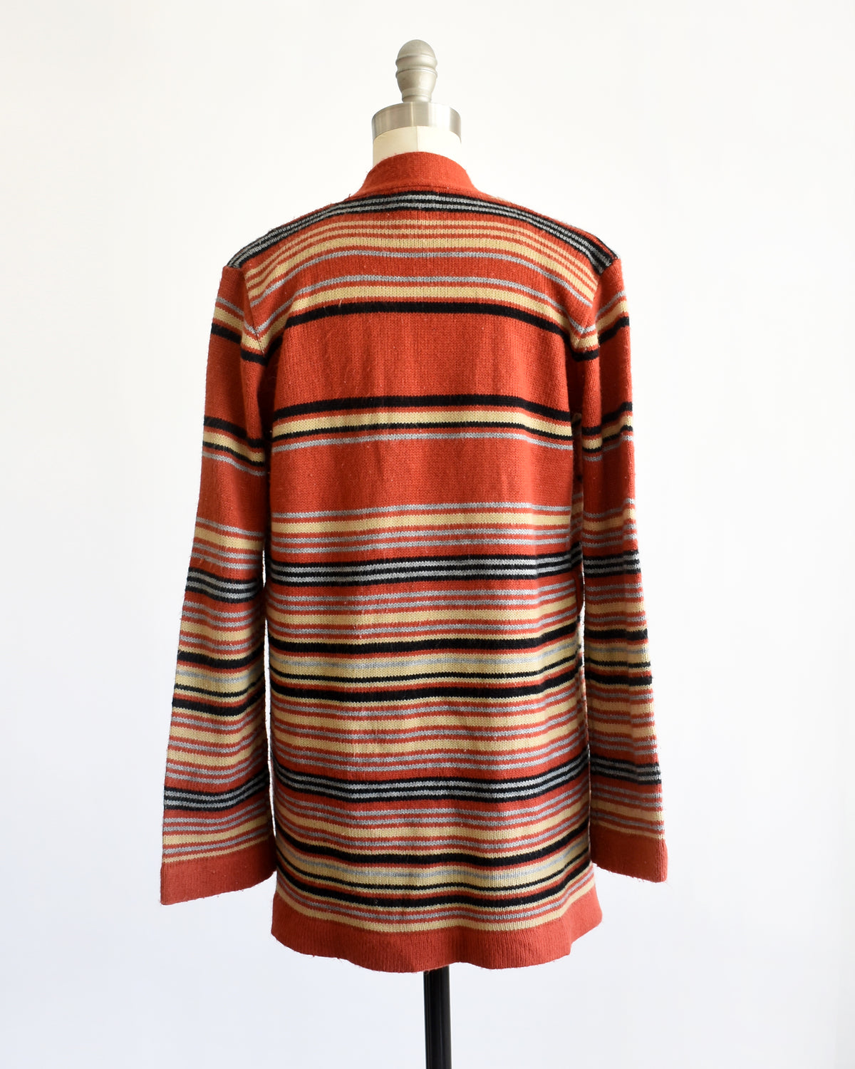 back view of  vintage 1970s long-sleeve open-front cardigan with a Southwestern geometric pattern, displayed on a white dress form mannequin against a plain white background.