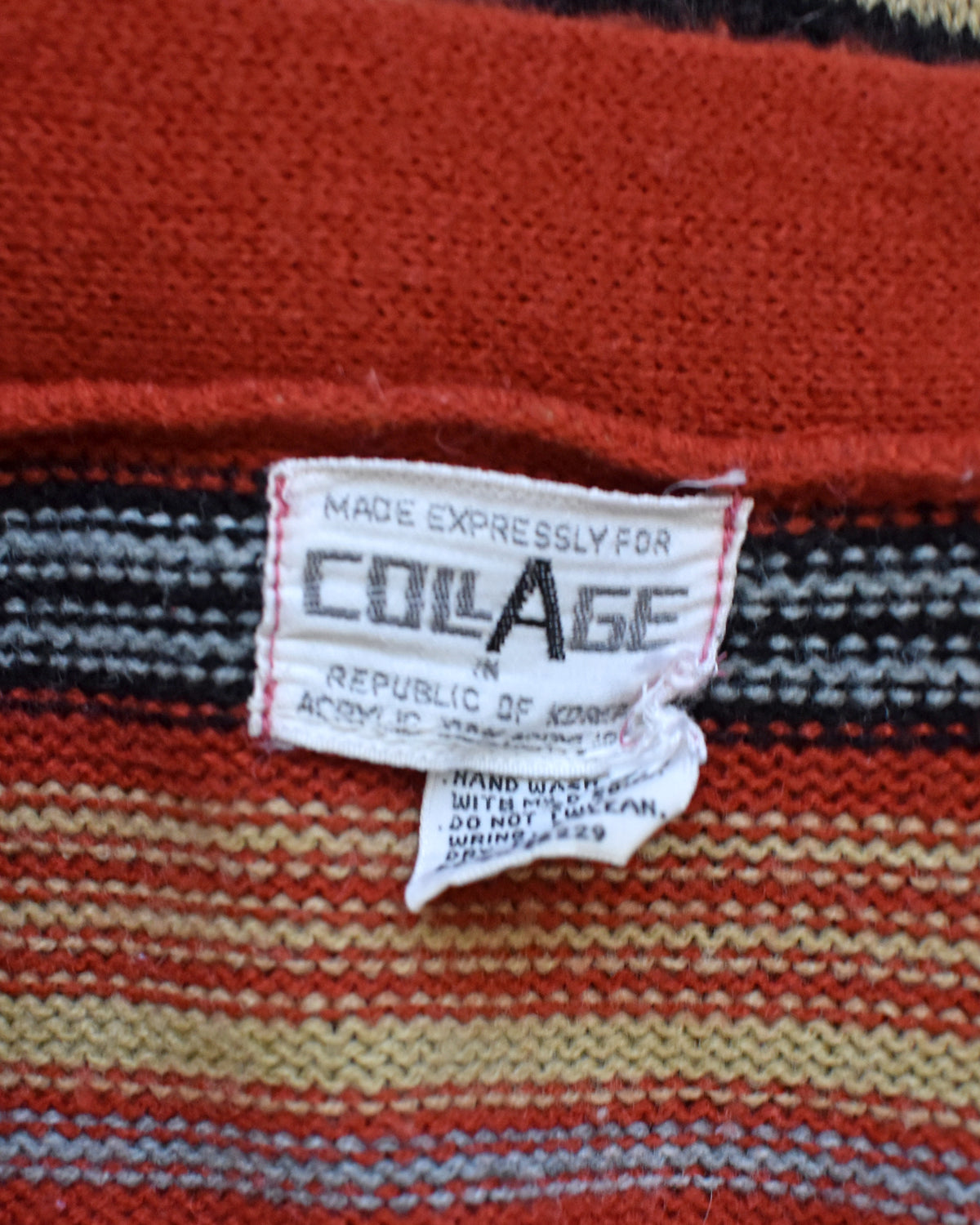 Close-up of a striped knit garment with a sewn-in label reading 'MADE EXPRESSLY FOR COLLAGE' and 'REPUBLIC OF KOREA'. 
