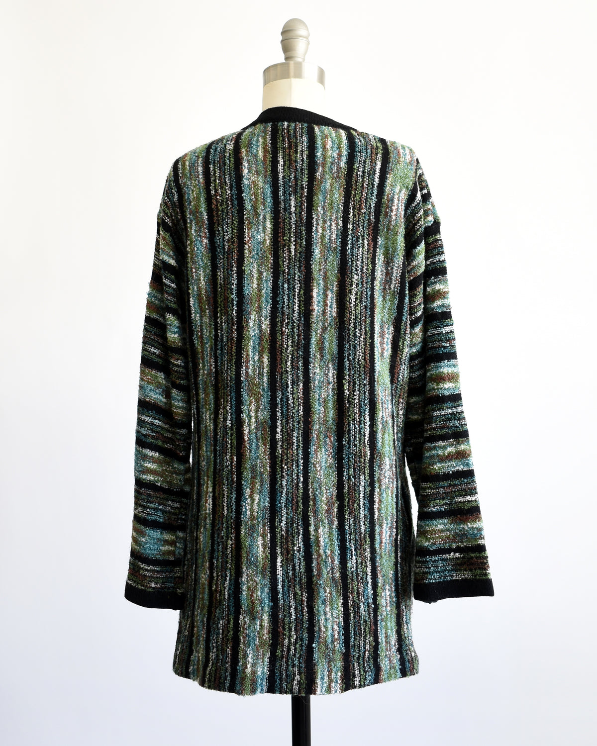 back view of a vintage 1970s open-front cardigan with wide bell sleeves, featuring a textured vertical stripe pattern in black, green, and white, displayed on a white dress form mannequin.