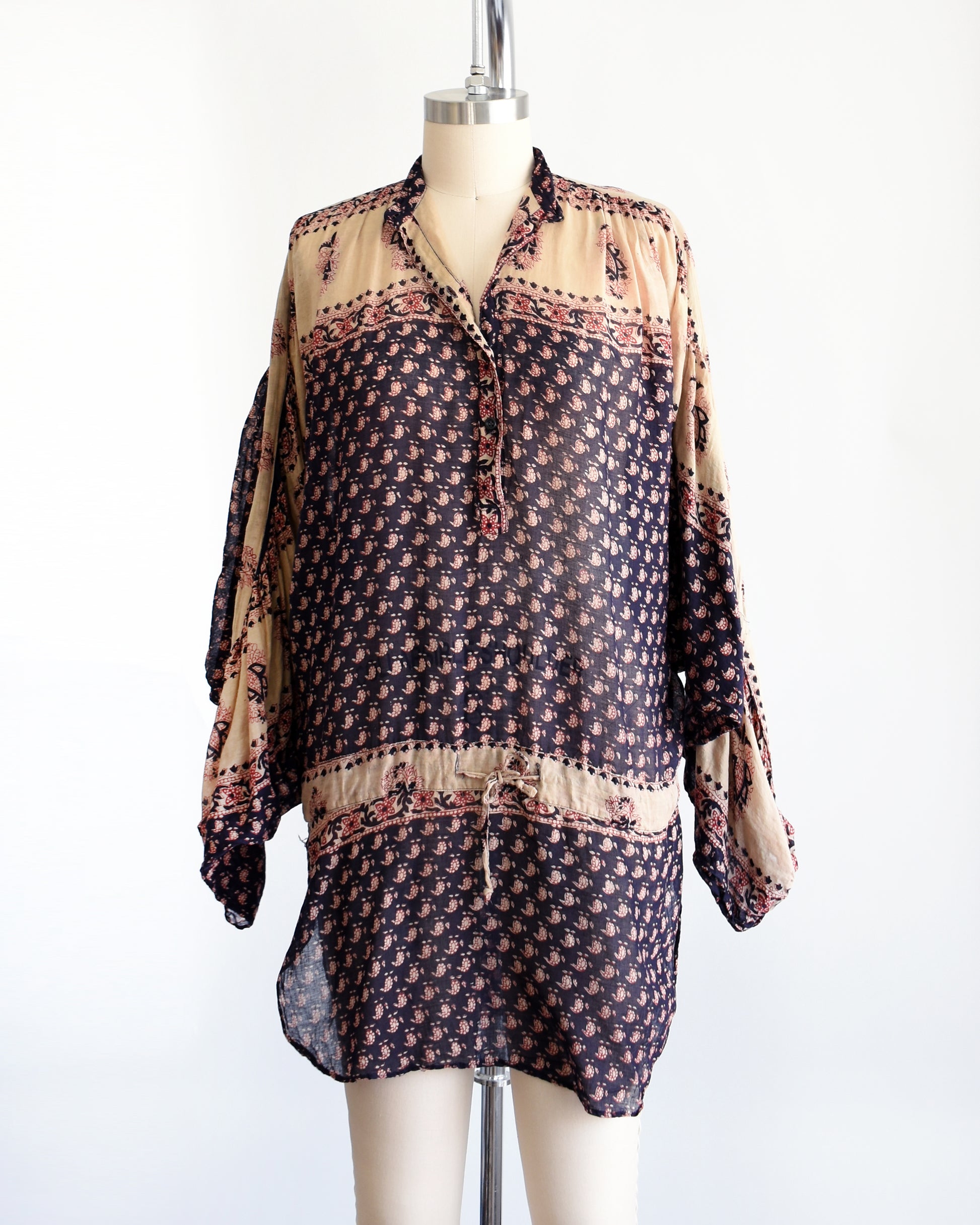 A vintage 1970s Indian cotton tunic made from thin, gauzy navy blue and light tan cotton with a red and navy floral block print. The tunic shown unbuttoned in this photo.