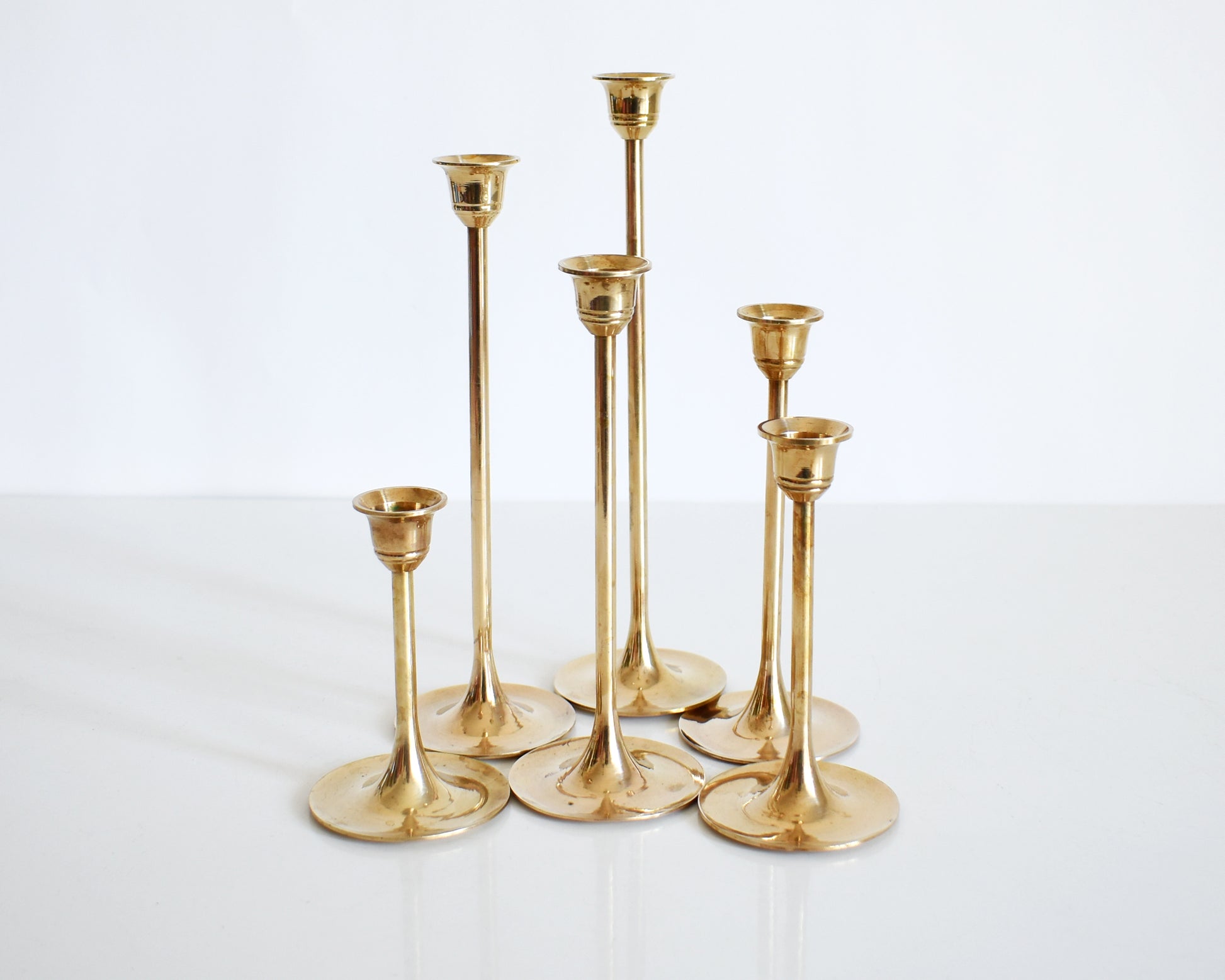 A vintage of six  of different vintage brass graduated candlesticks in a group.