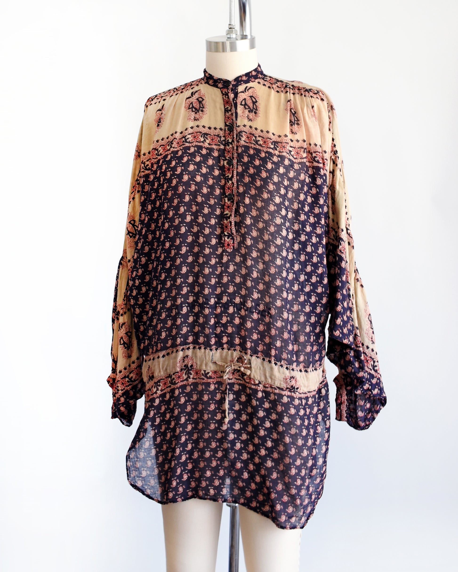 Side front view of a A vintage 1970s Indian cotton tunic made from thin, gauzy navy blue and light tan cotton with a red and navy floral block print