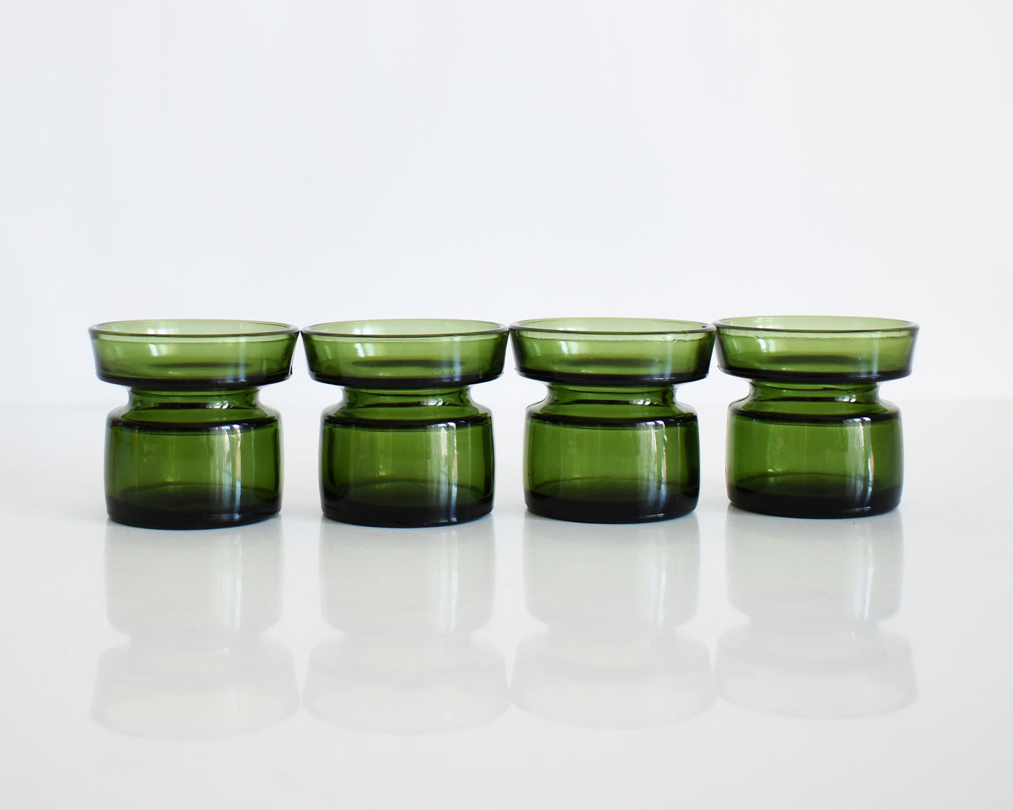 Set of four vintage 1960s green glass Dansk candle holders in a row