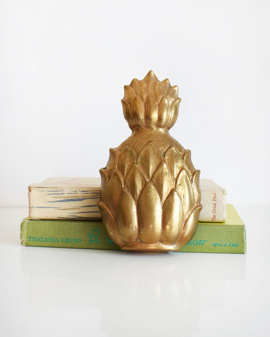 a vintage brass pineapple door knocker set against two books