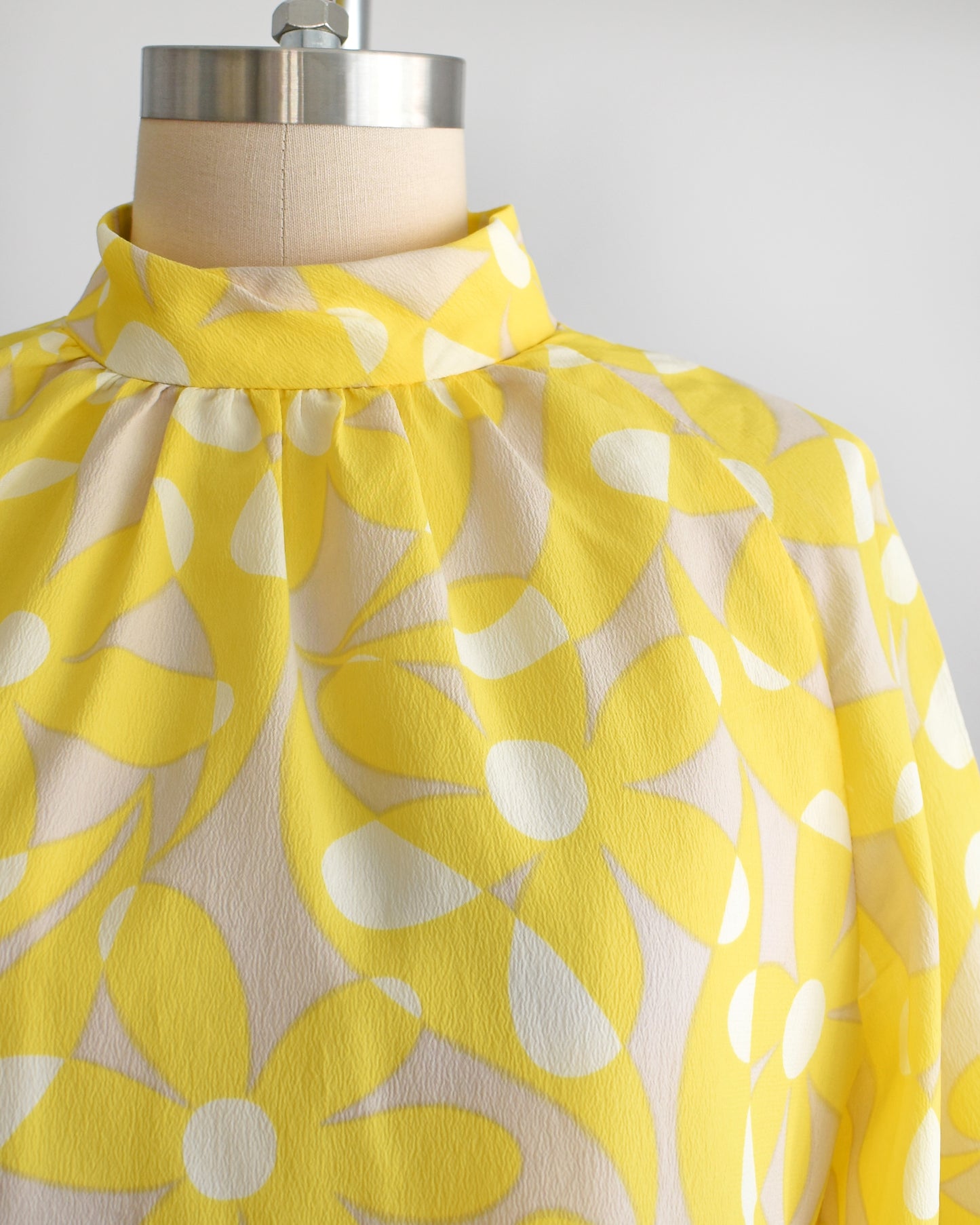Close up of the mockneck collar and yellow floral print