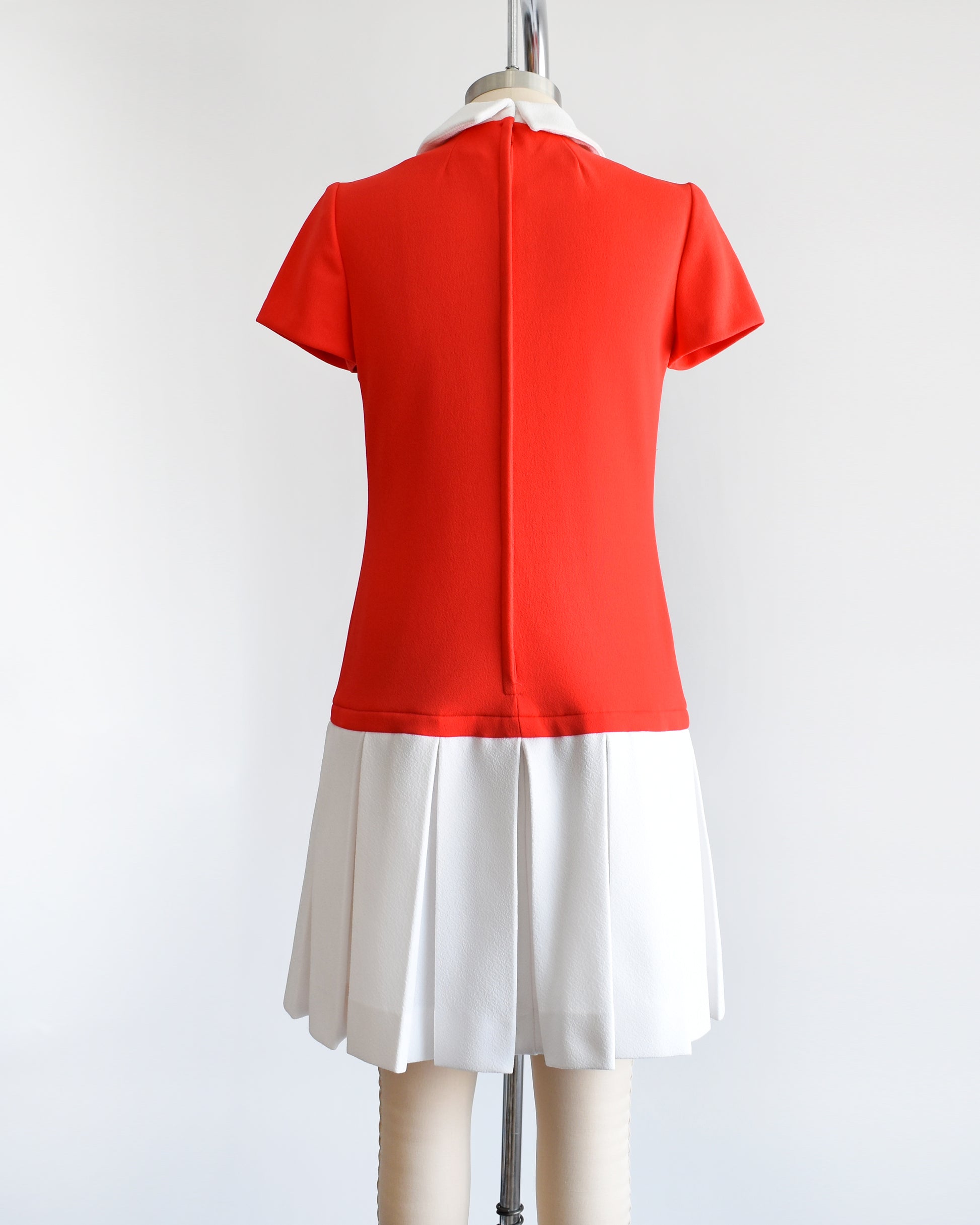 Back view of  a vintage late 1960s early 1970s drop waist dress features a red bodice and white pleated skirt. Zipper up the back