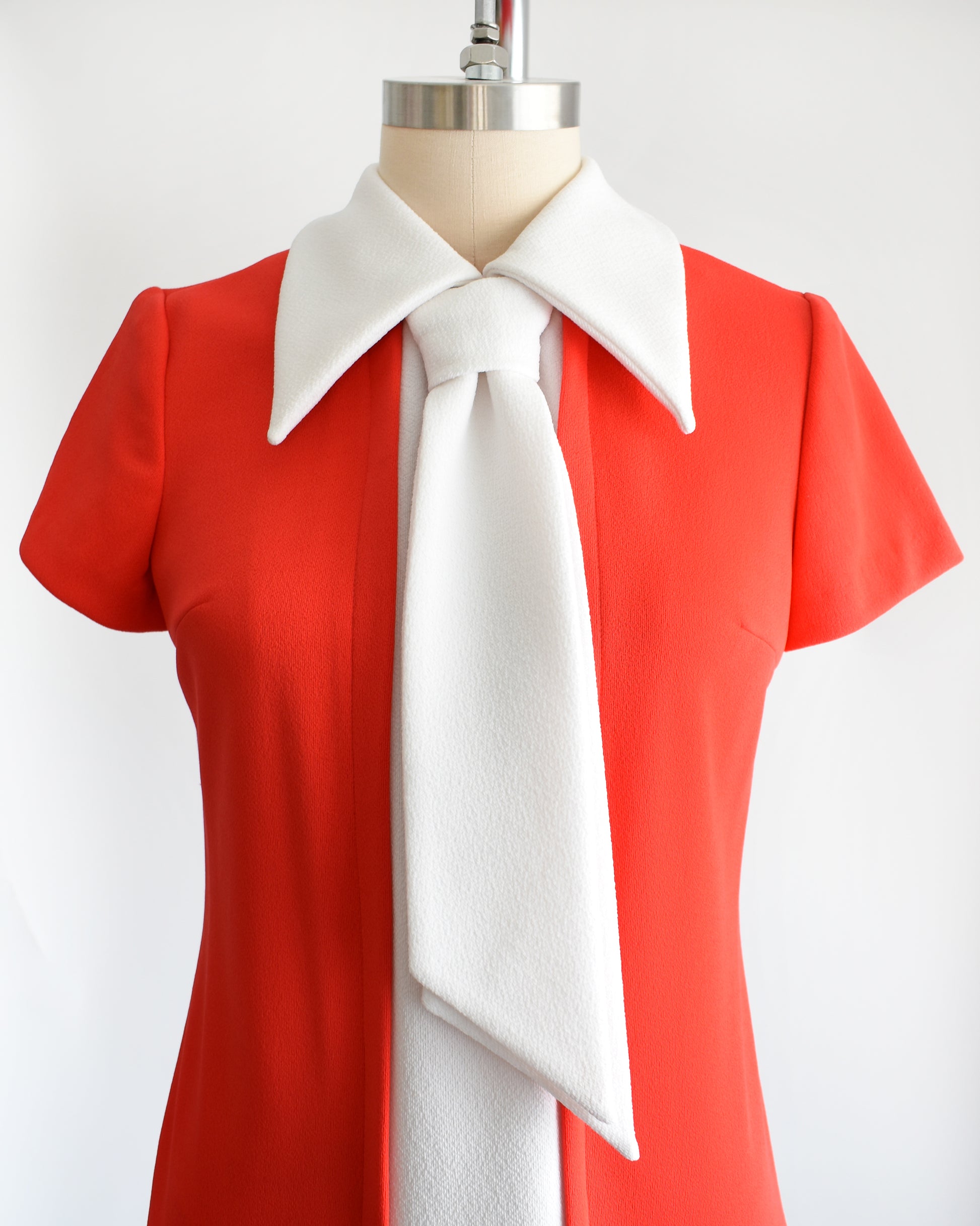 Close up of the red bodice that features a white collared neckline and ascot tie