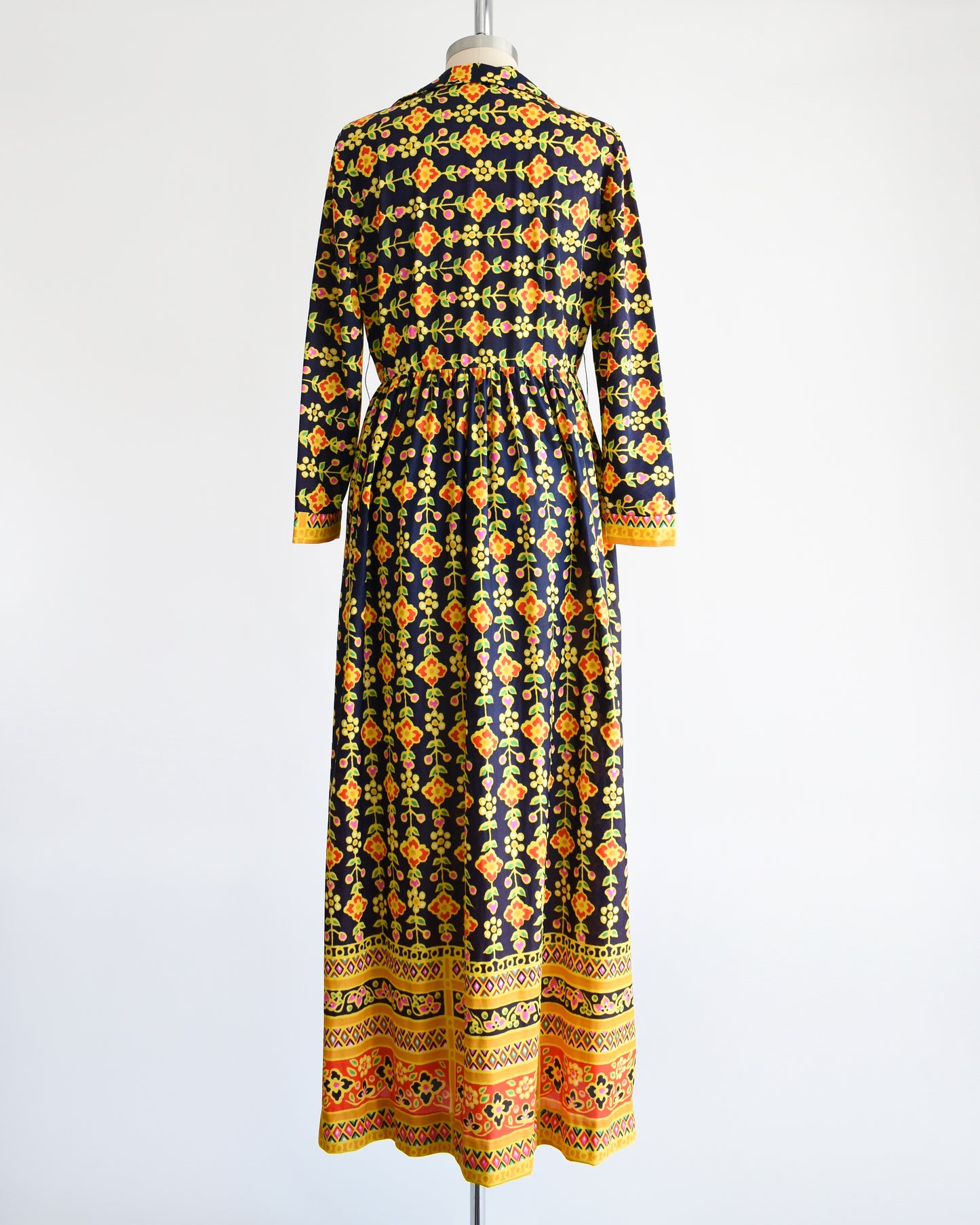 Back view of a vintage 1970s navy blue maxi dress with a colorful striped floral print.