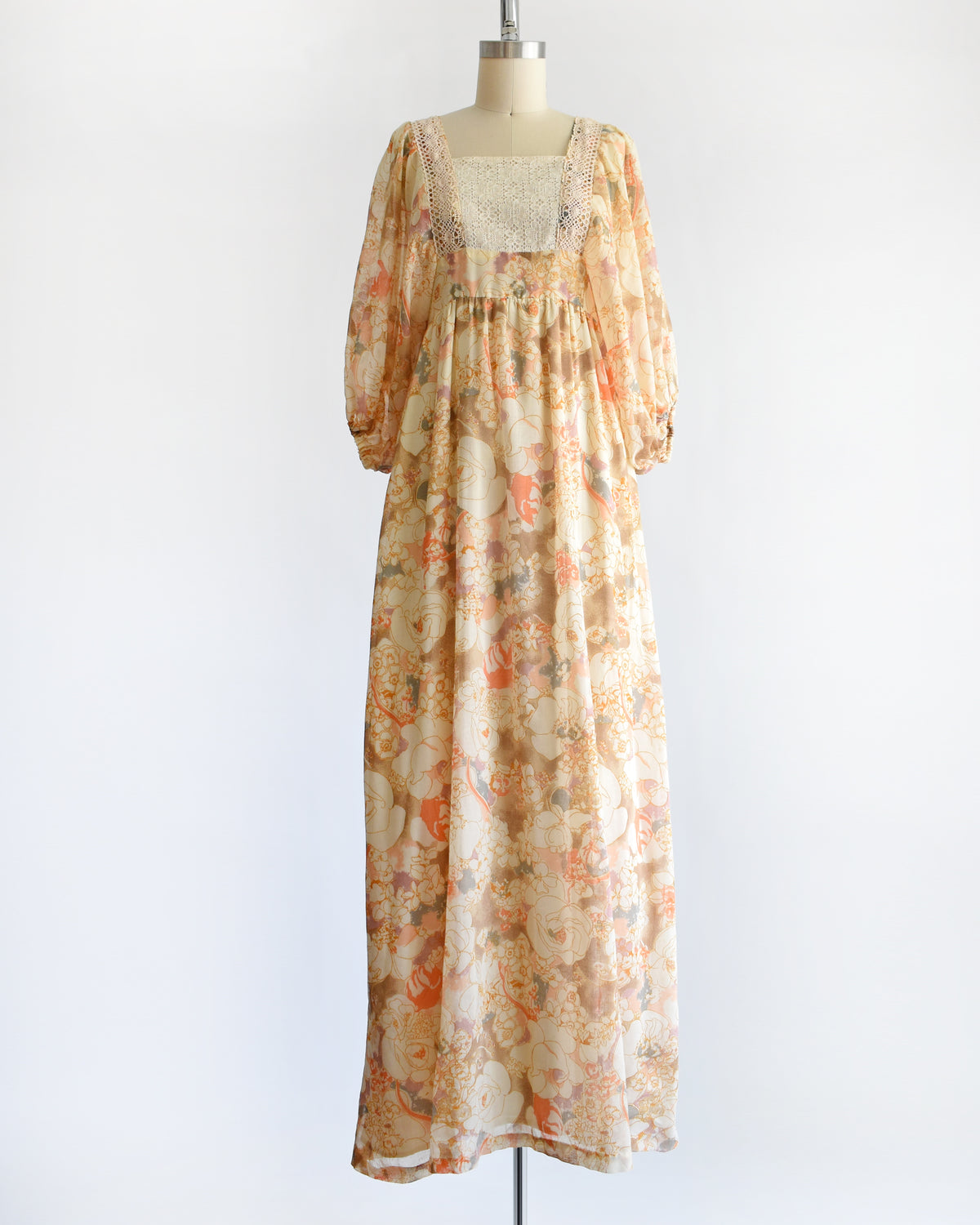 a vintage 1970s orange floral lace maxi dress on a dress form against a white background