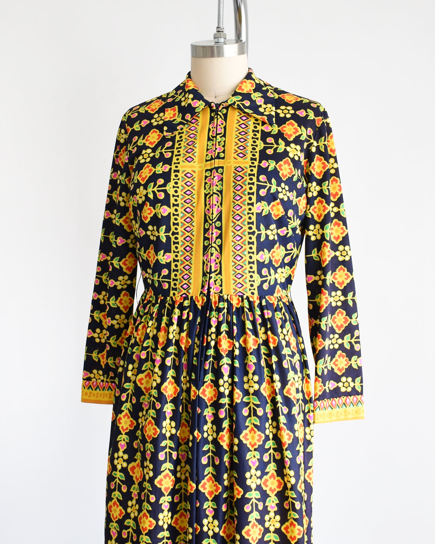 Side front view of a vintage 1970s navy blue maxi dress with a colorful striped floral print.