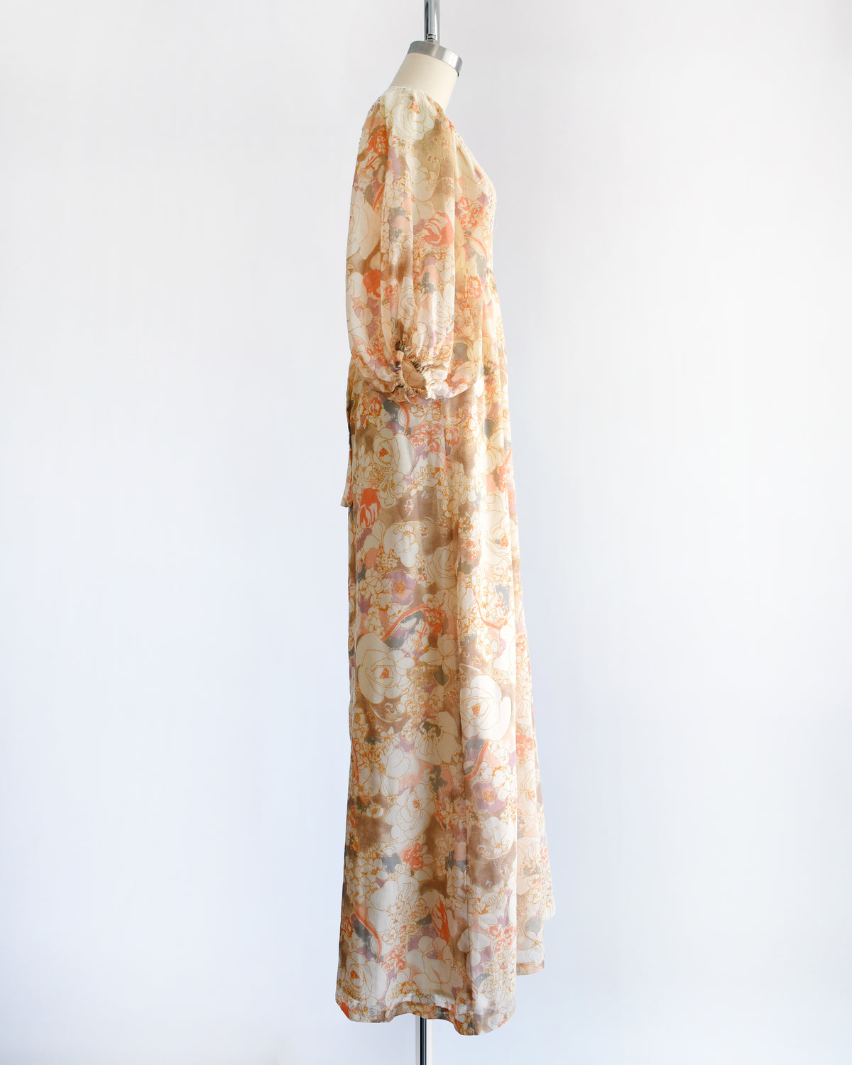 side view of a vintage 1970s orange floral lace maxi dress on a dress form against a white background