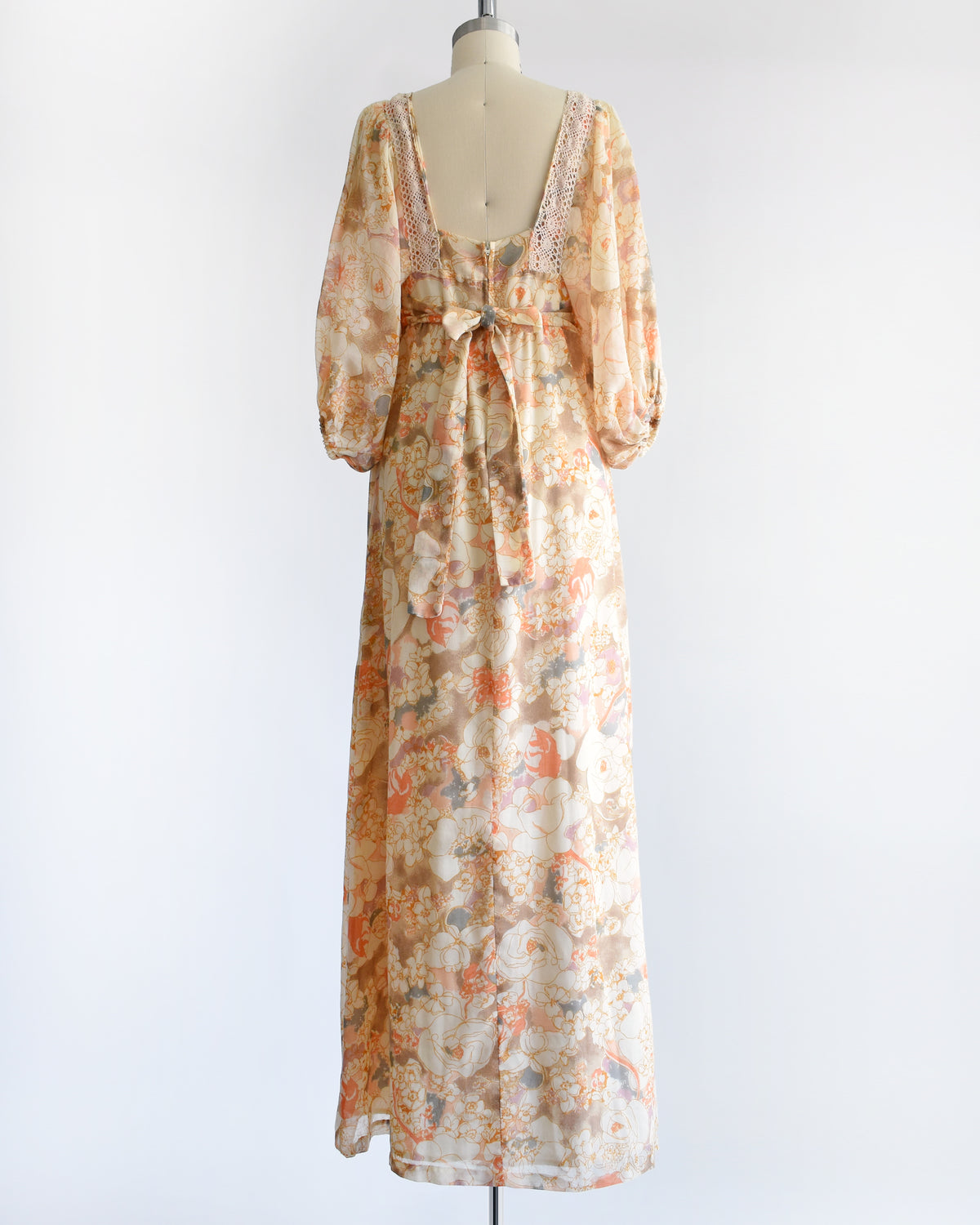 back view of a vintage 1970s orange floral lace maxi dress on a dress form against a white background