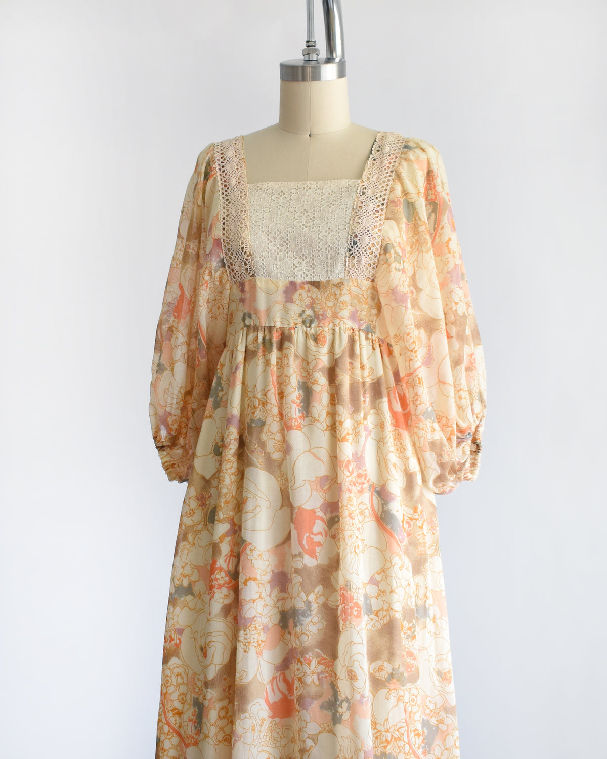 side front view of a vintage 1970s orange floral lace maxi dress on a dress form against a white background