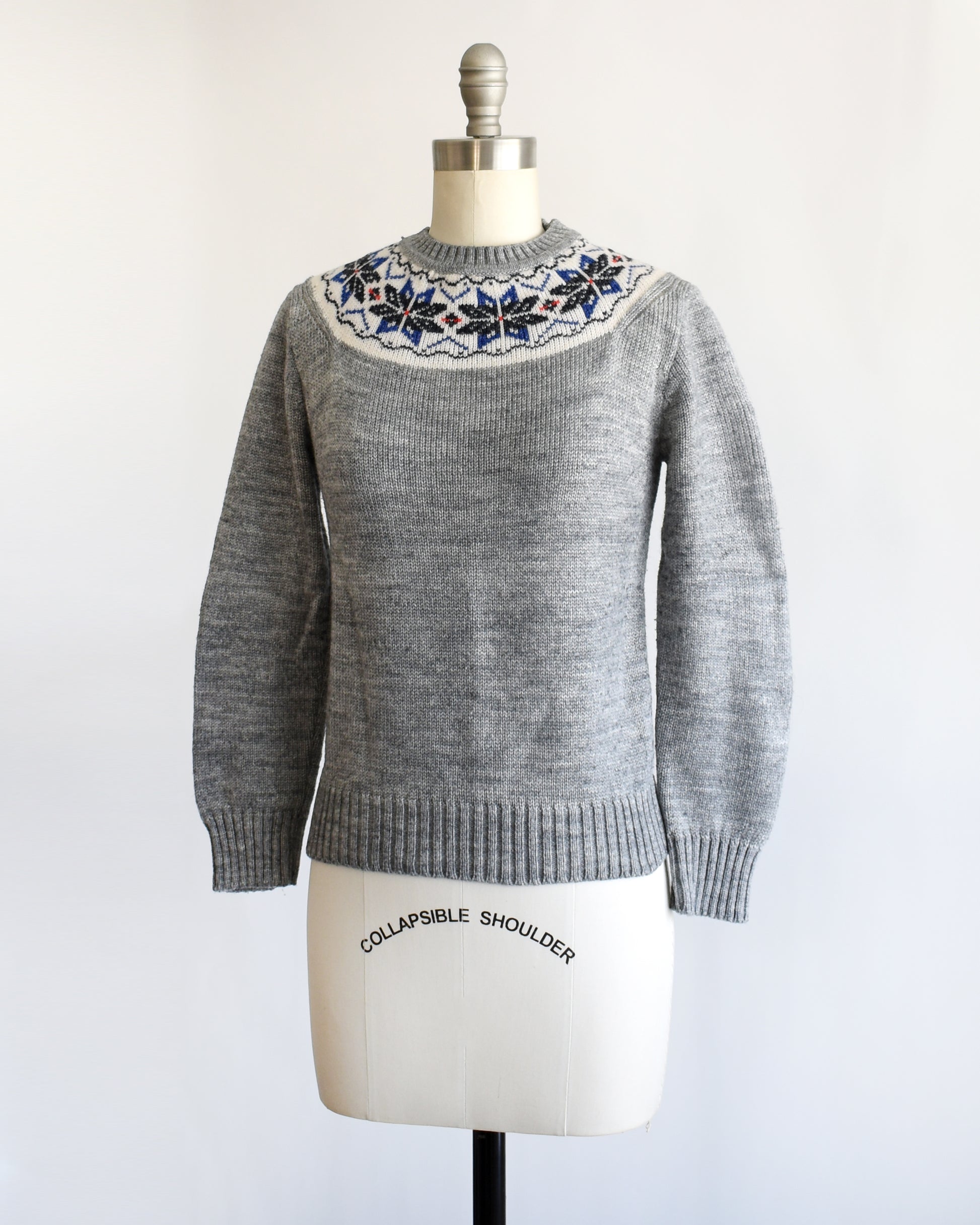 side front view of back view of a vintage 70s gray sweater with snowflake patterned neckline on a mannequin against a white background