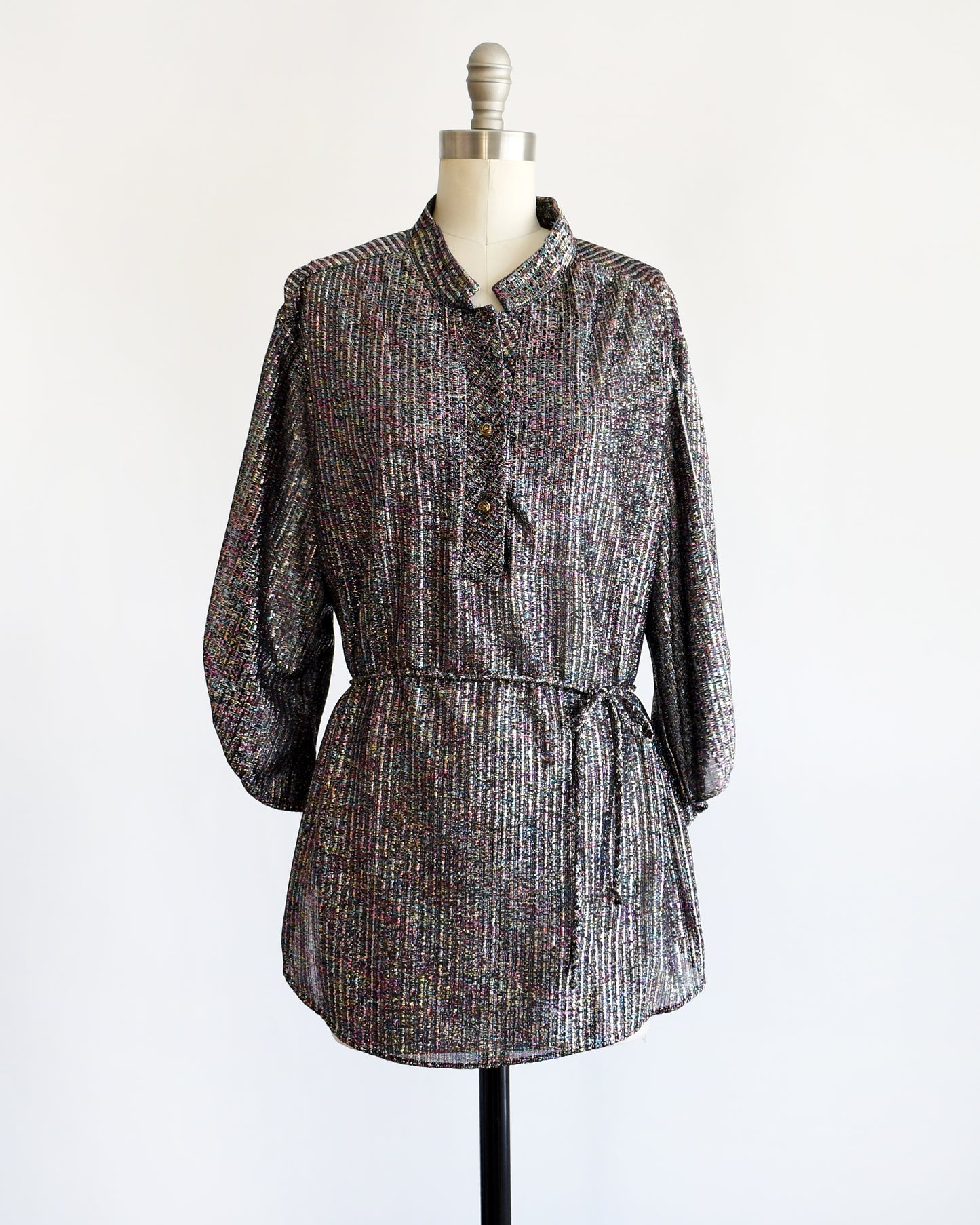 a vintage 1970s black rainbow metallic blouse on a dress form against a white background