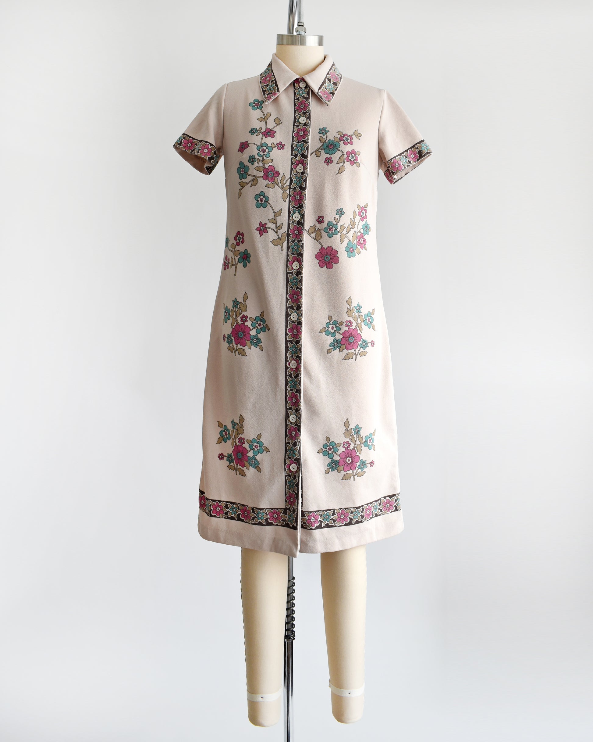 A vintage 1970s light brown mod dress with button front that features a blue and pink floral print 