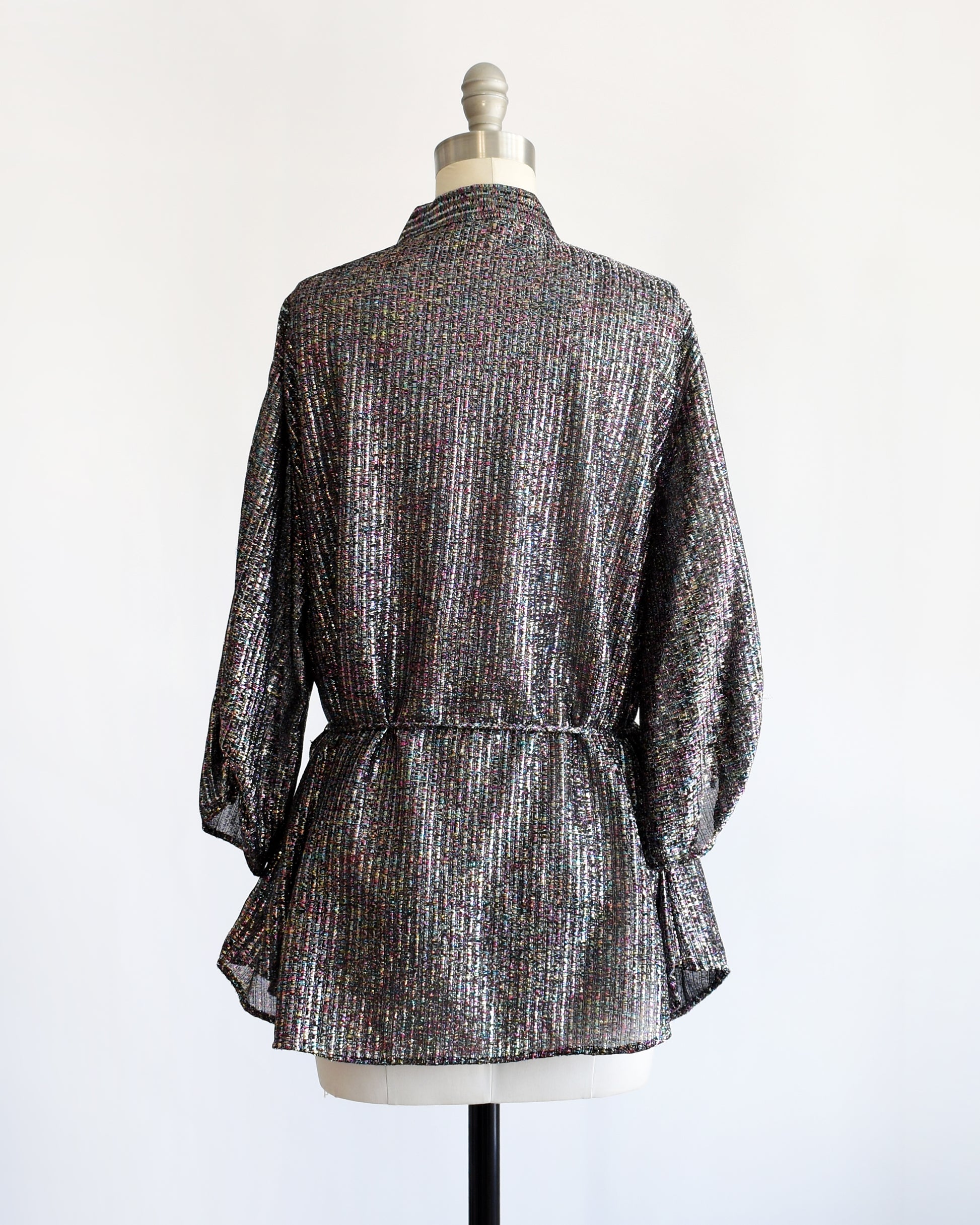 back view of a vintage 1970s black rainbow metallic blouse on a dress form against a white background