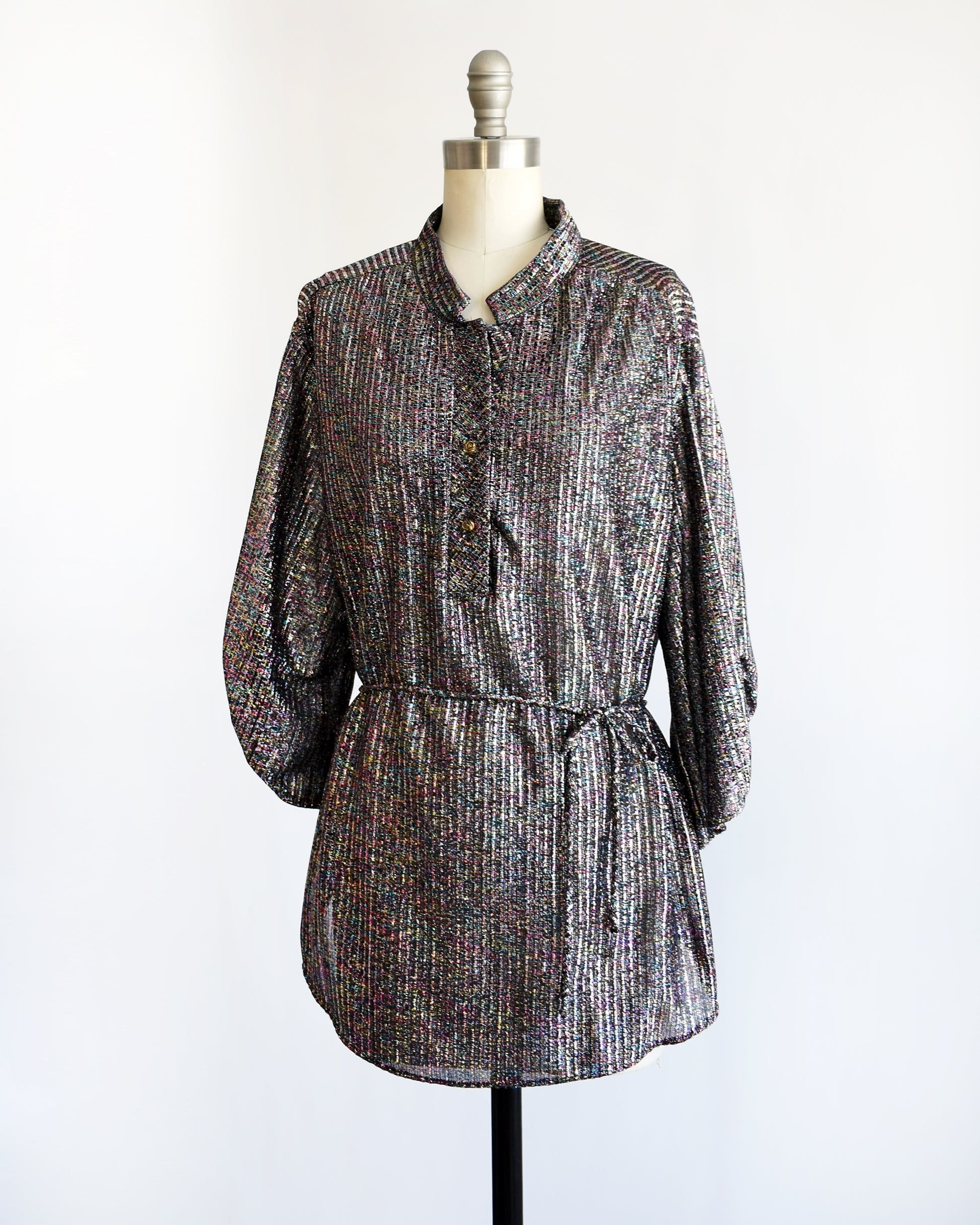 side view of a vintage 1970s black rainbow metallic belted blouse on a dress form against a white background