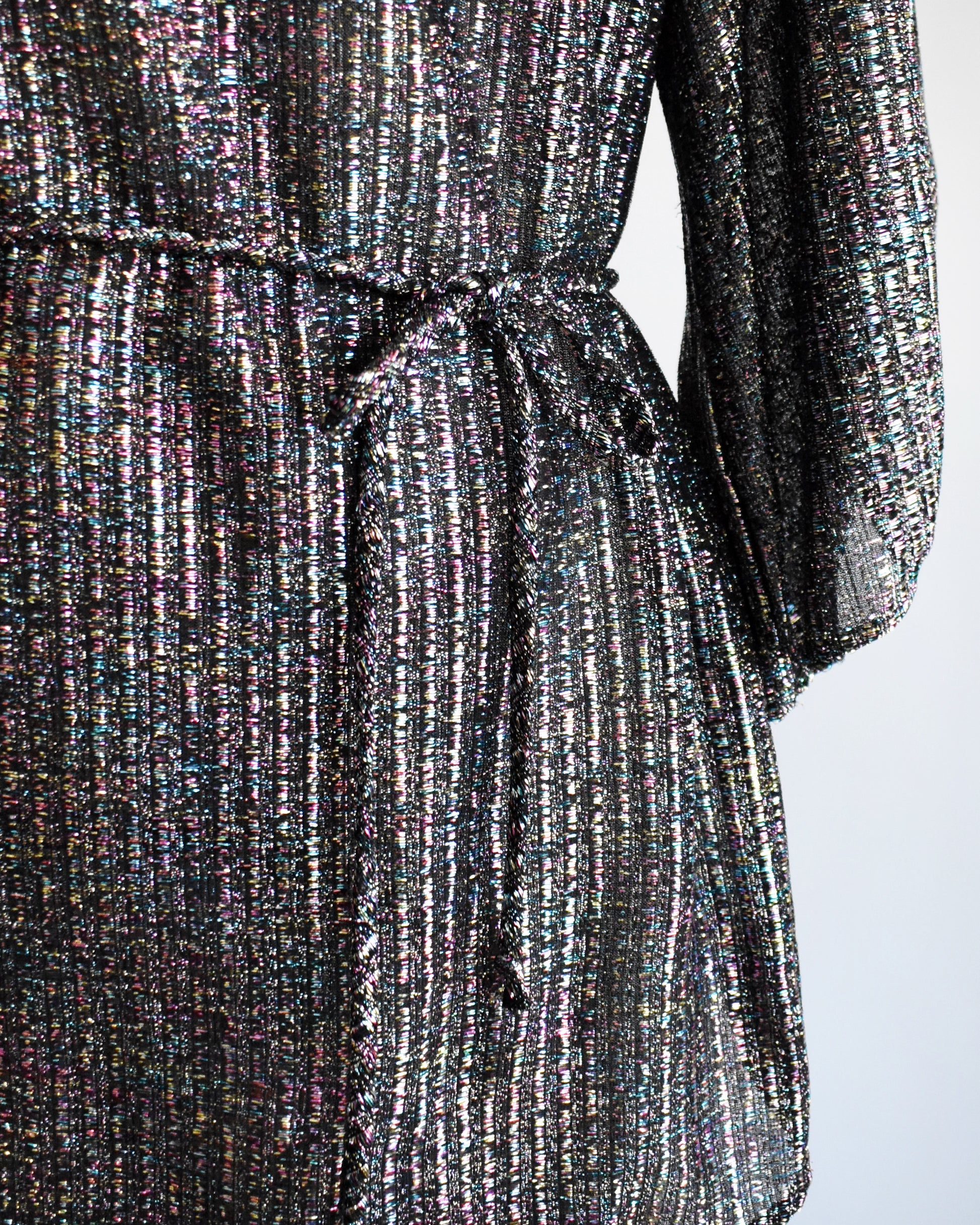 Close-up of a textured, multicolored fabric with a tie detail on a white background