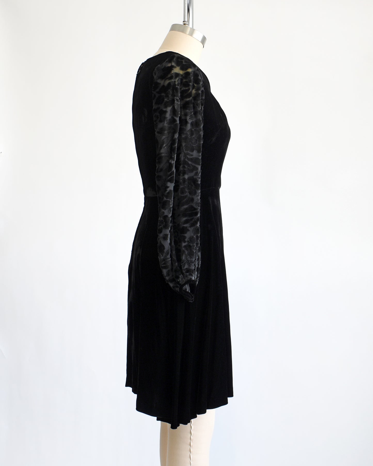 side view of a vintage 1960s black velvet cocktail dress with black velvet burnout long sleeves