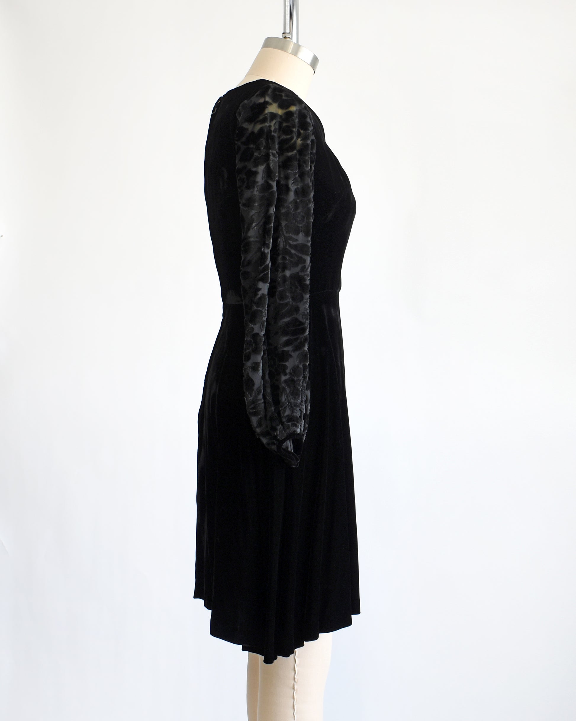 side view of a vintage 1960s black velvet cocktail dress with black velvet burnout long sleeves