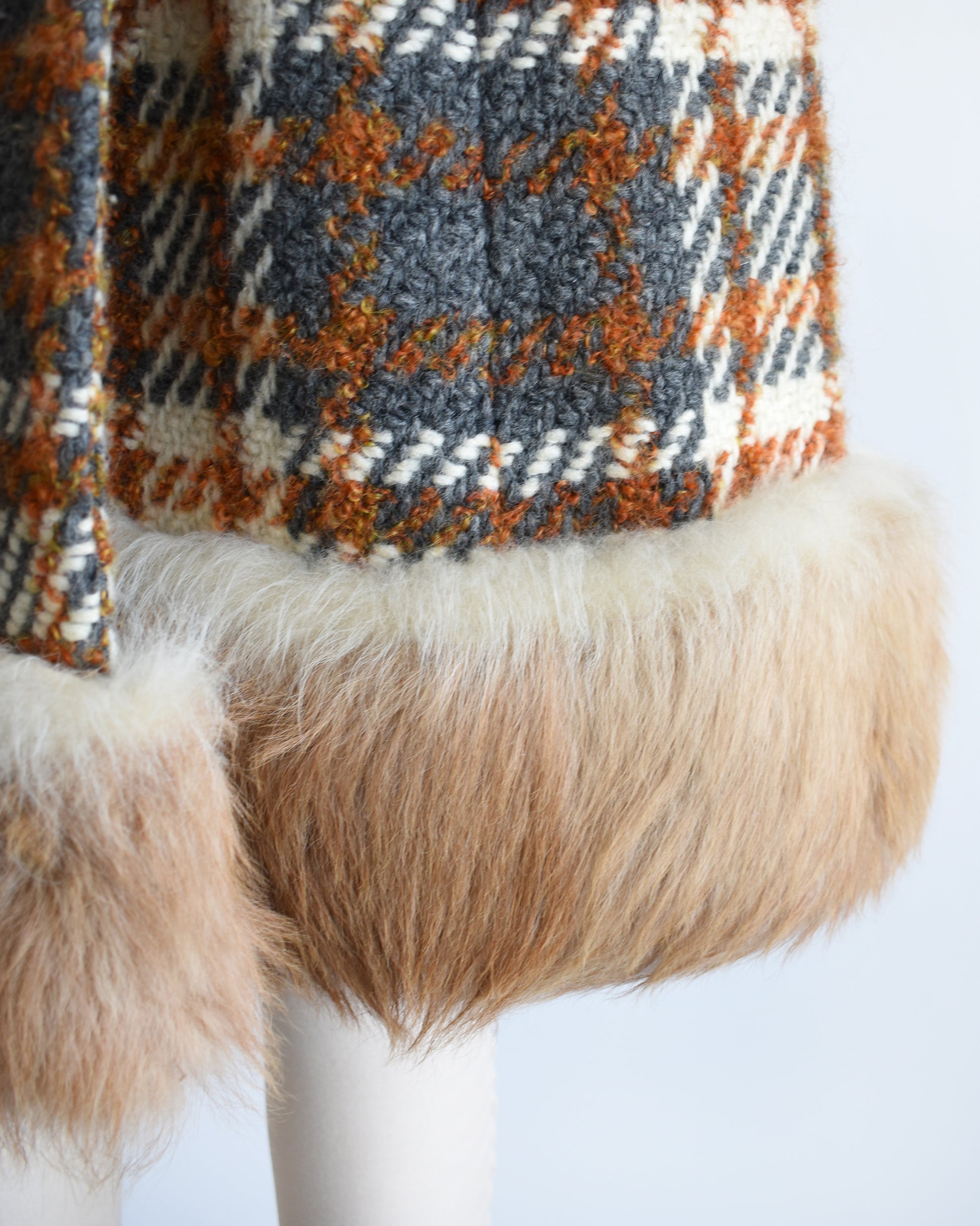 close up of the fur trim on the hem of a vintage 1960s plaid wool coat with guanaco fur trim