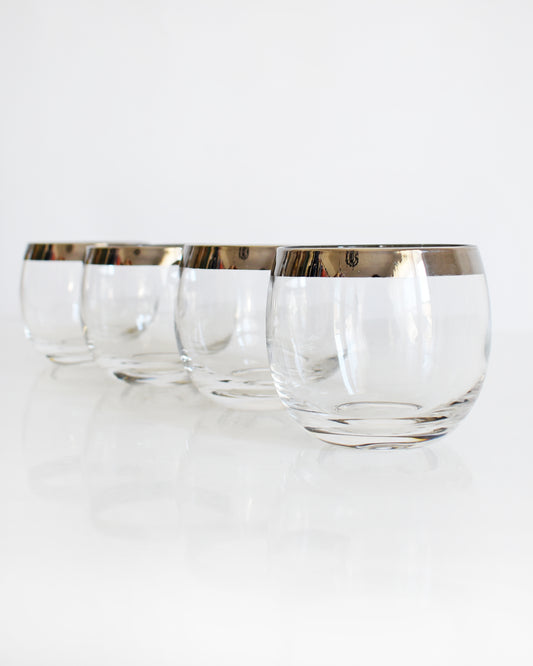 set of four vintage 1960s round roly poly cocktail glasses that have silver rims at the top.