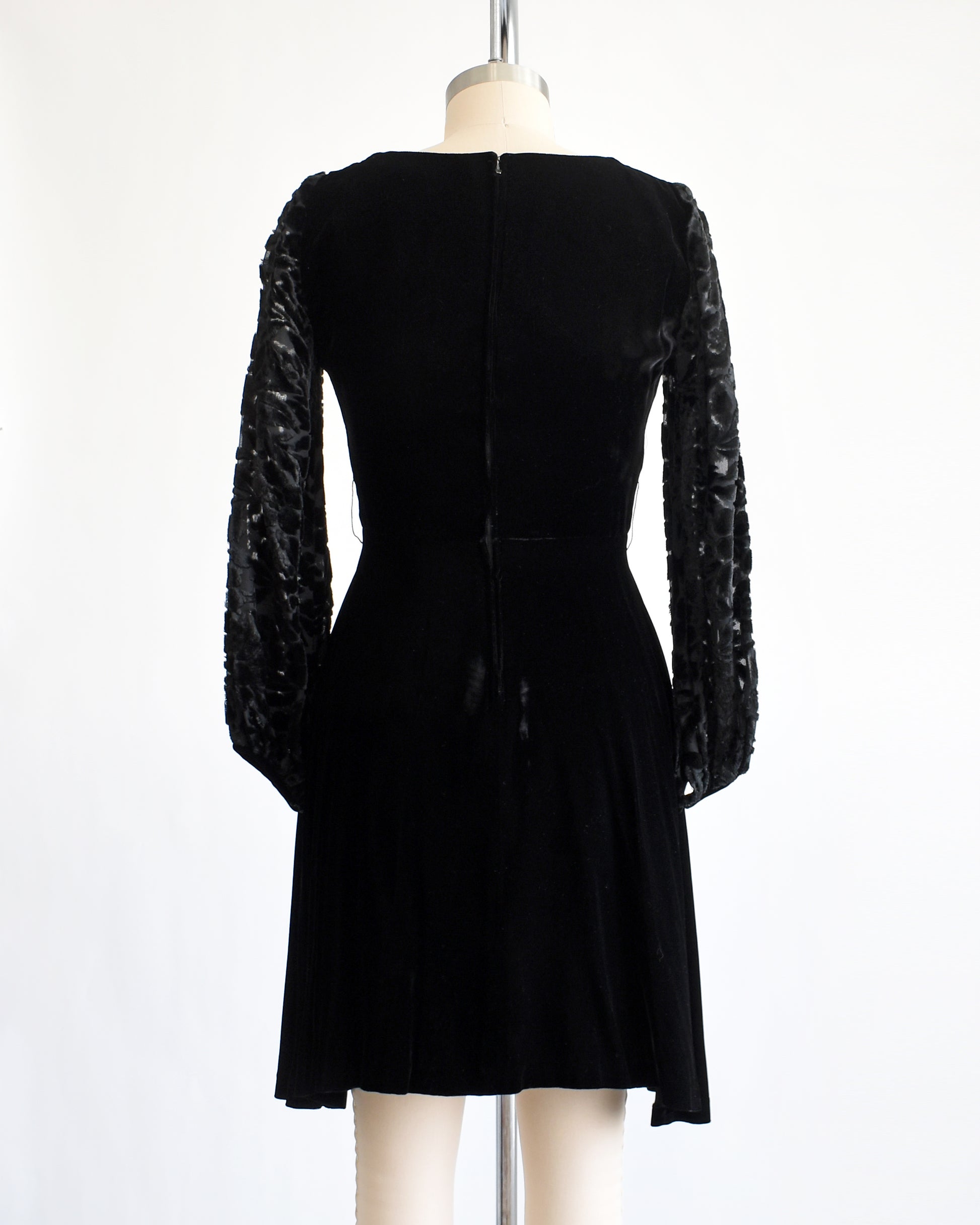 back view of a vintage 1960s black velvet cocktail dress  with black velvet burnout long sleeves