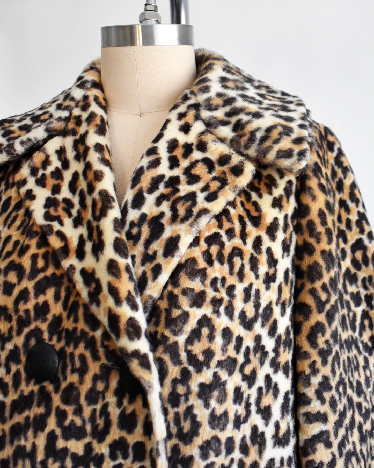 close up of the collar of a vintage late 1960s early 1970s faux fur leopard print coat with four black buttons