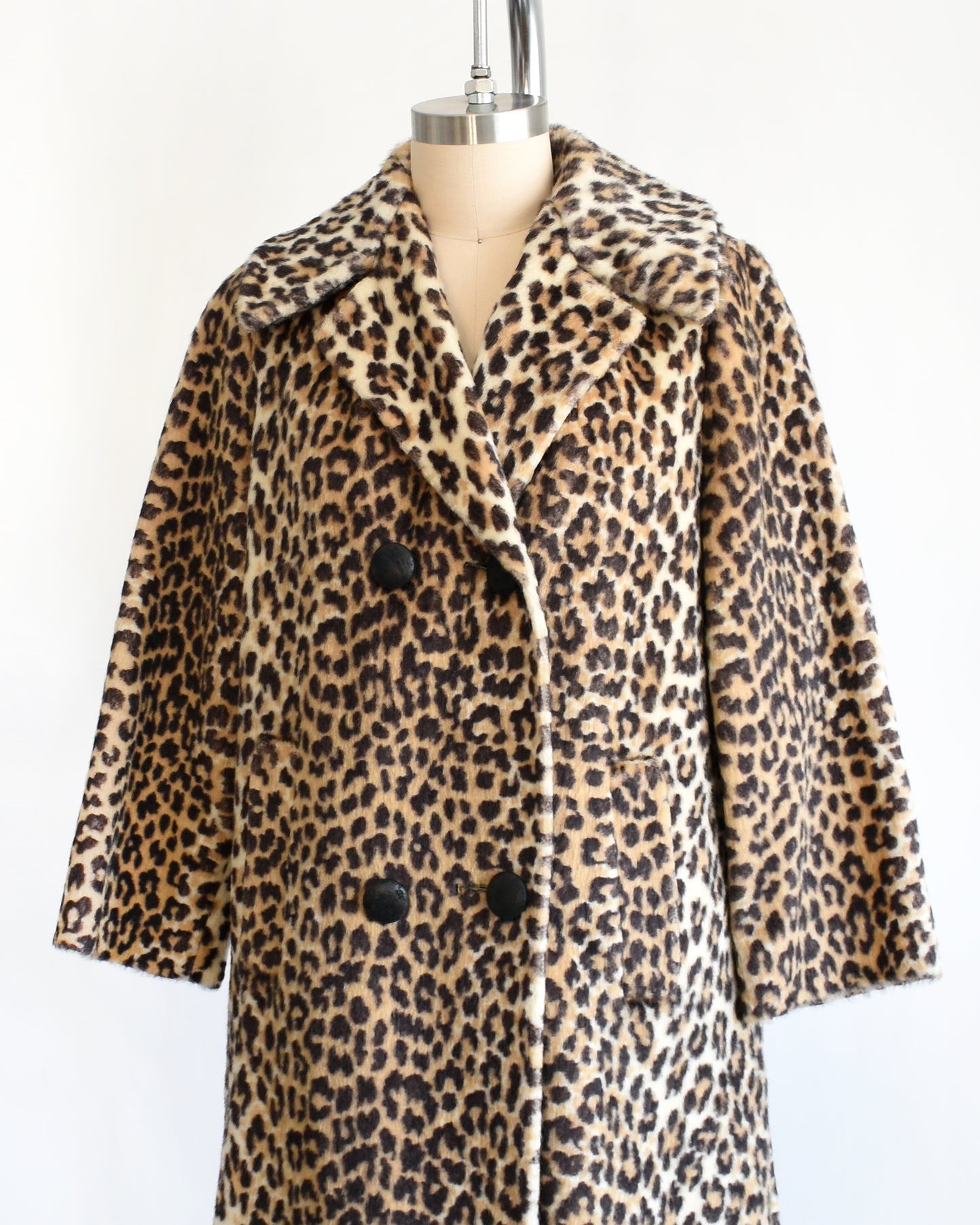 side front view of a vintage late 1960s early 1970s faux fur leopard print coat with four black buttons