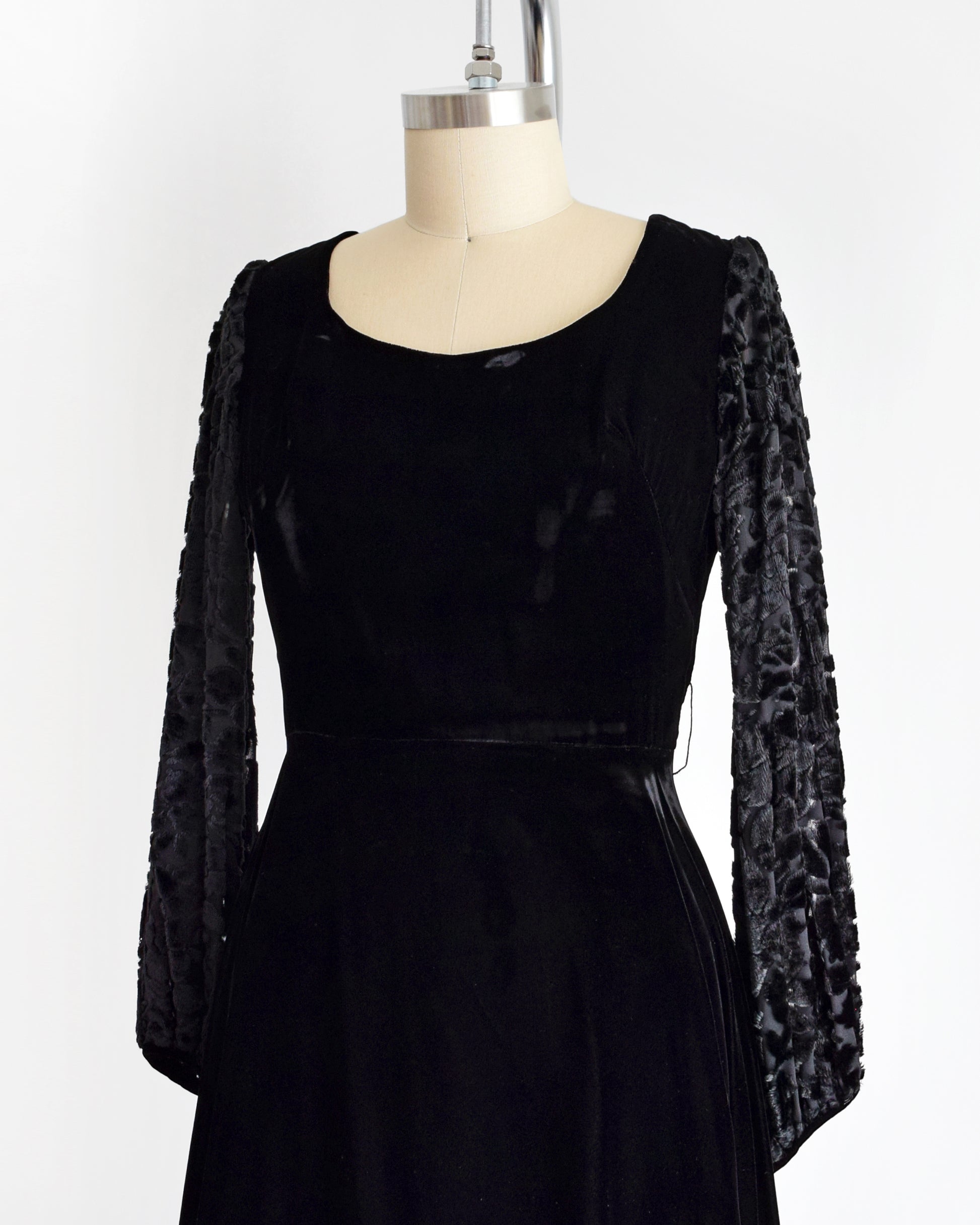 side front view of a vintage 1960s black velvet cocktail dress with black velvet burnout long sleeves