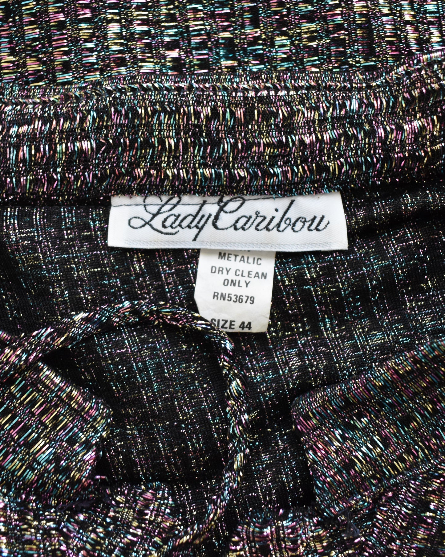 Close-up of a metallic fabric with 'Lady Caribou' label on a textured background