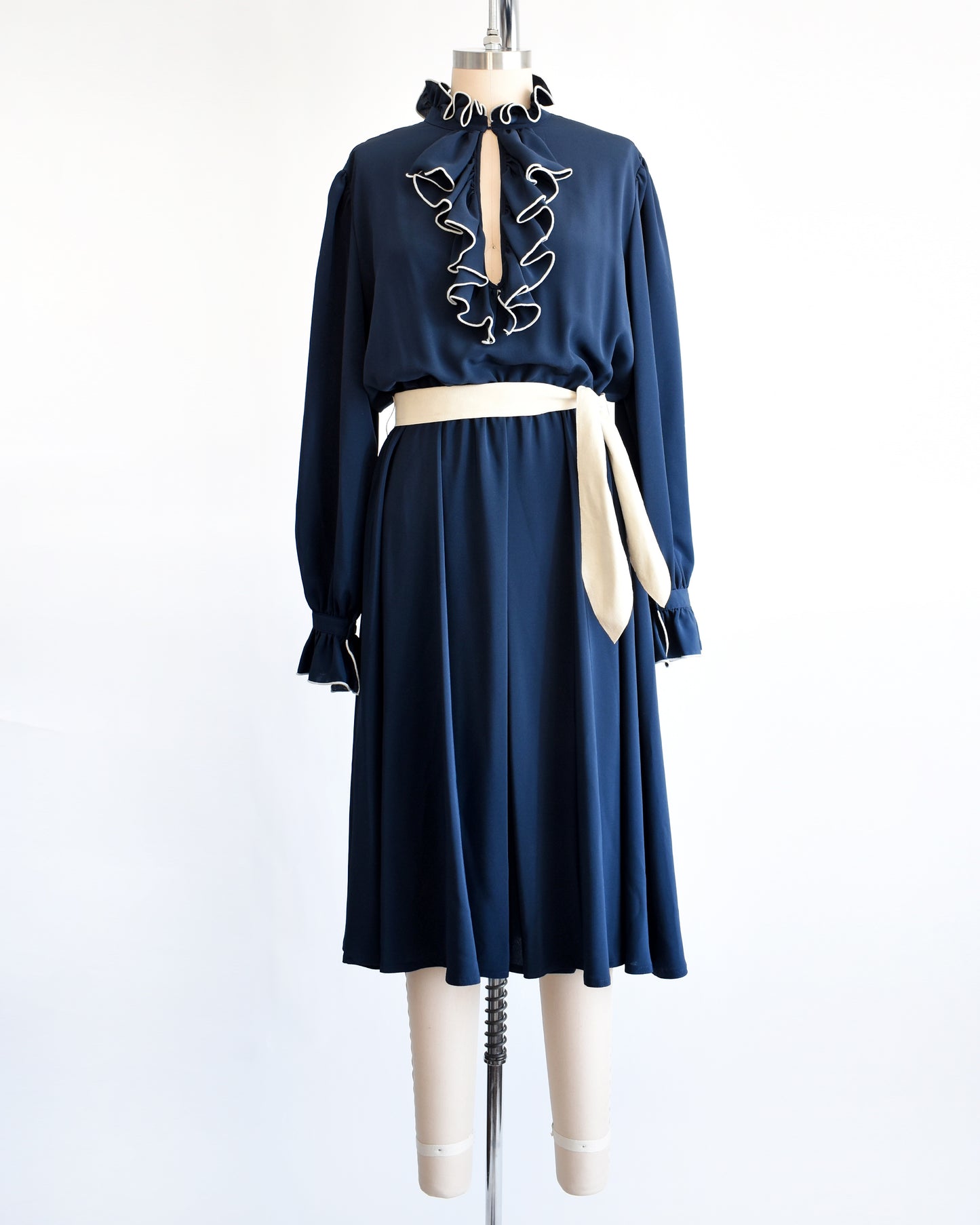 a vintage late 1970s early 1980s navy ruffled dress with cream colored tie belt