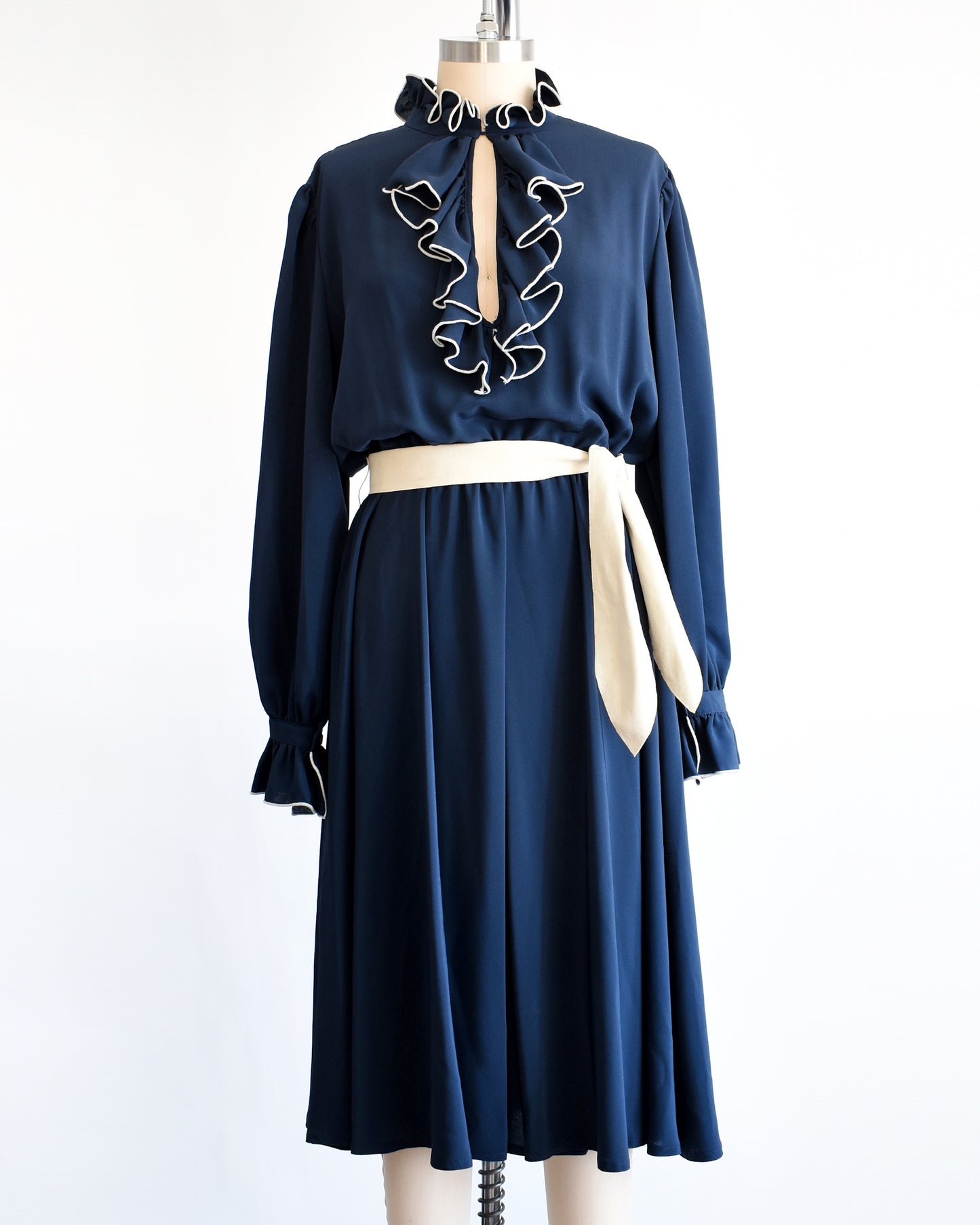 a vintage late 1970s early 1980s navy ruffled dress with cream colored tie belt