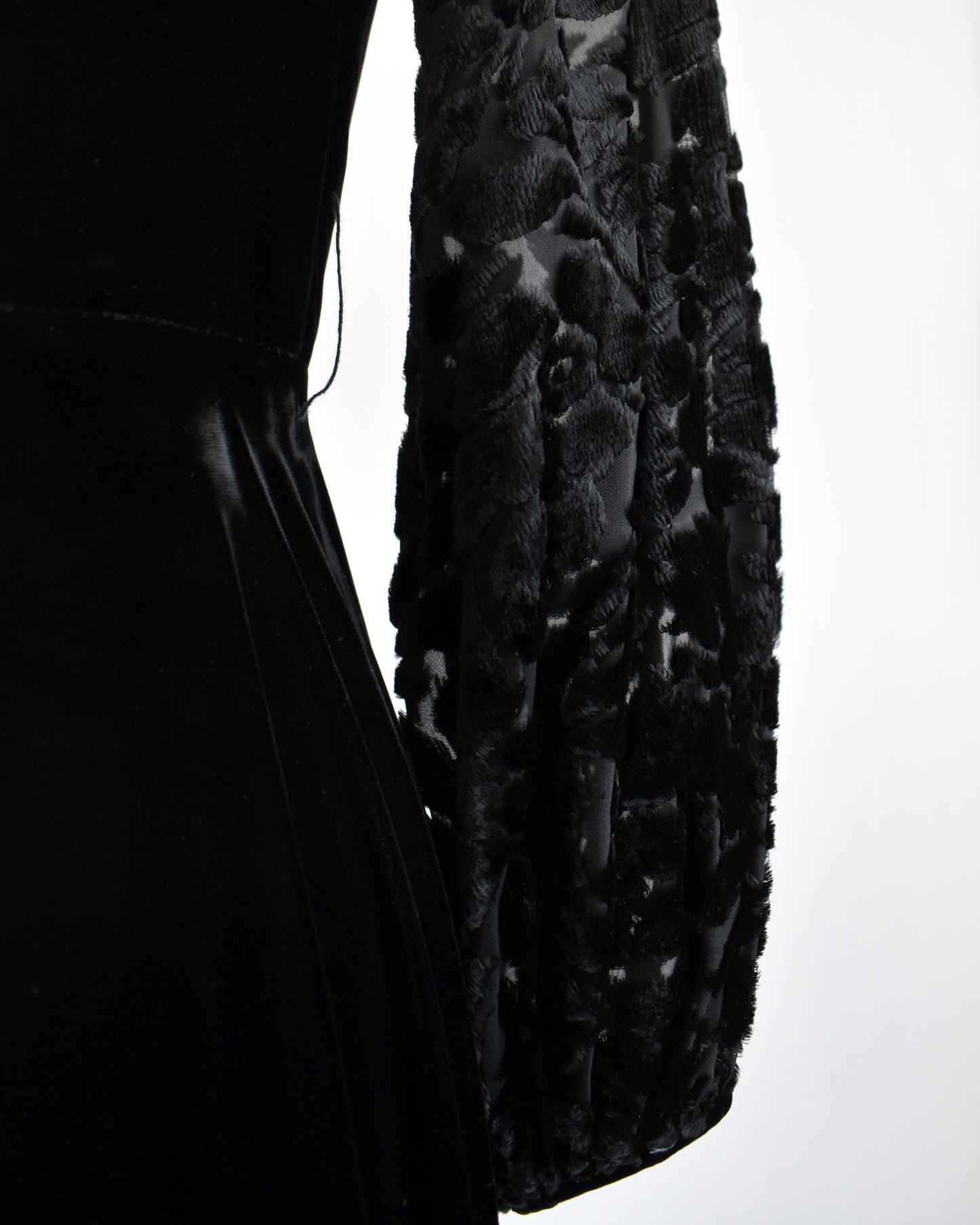 close up of the waist line and long sleeves of a vintage 1960s black velvet cocktail dress