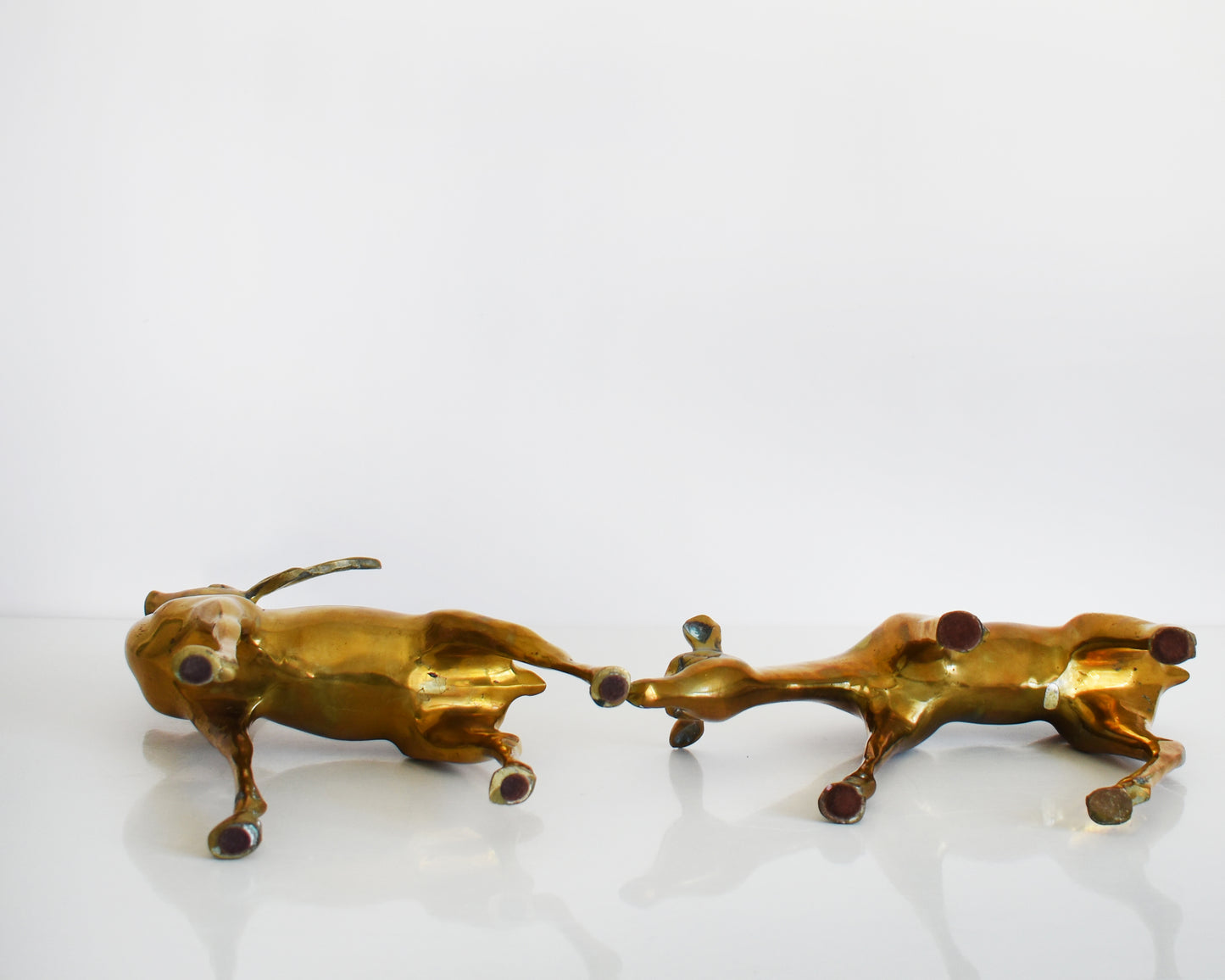 A pair of brass deer lying down showing their underside