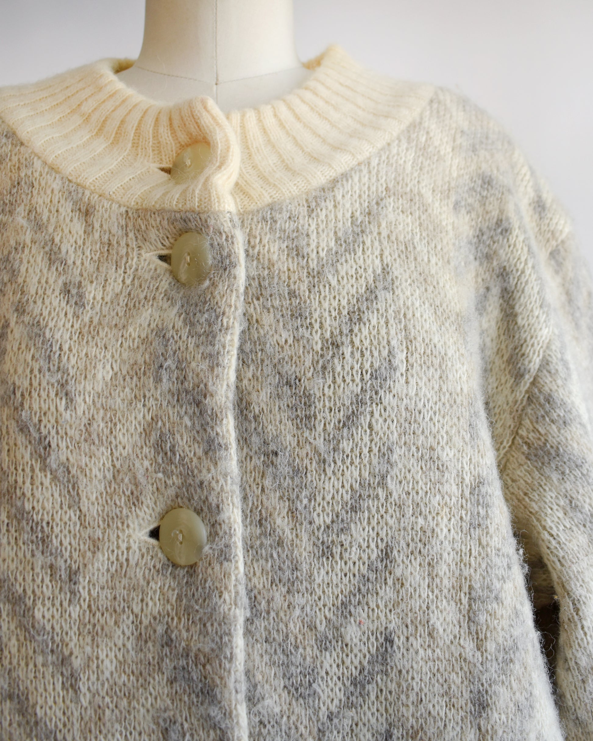 Close-up of a knitted cardigan with a mannequin wearing it against a white background