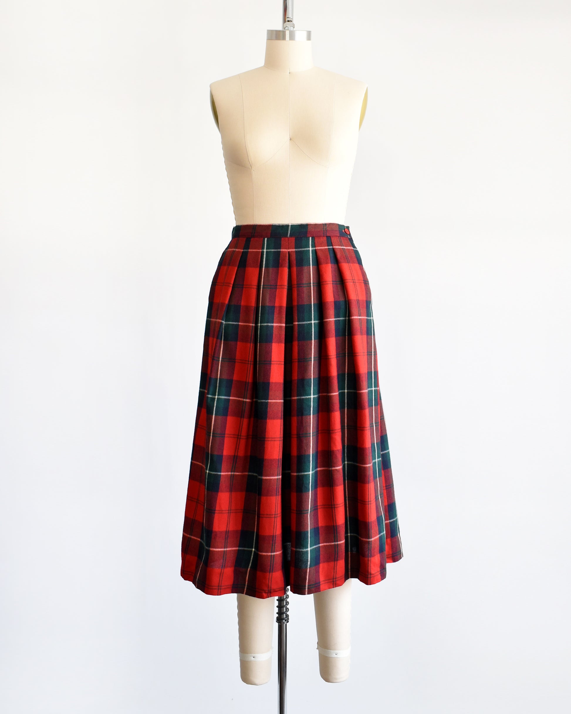A vintage 80s red and green plaid pleated skirt on a dress form