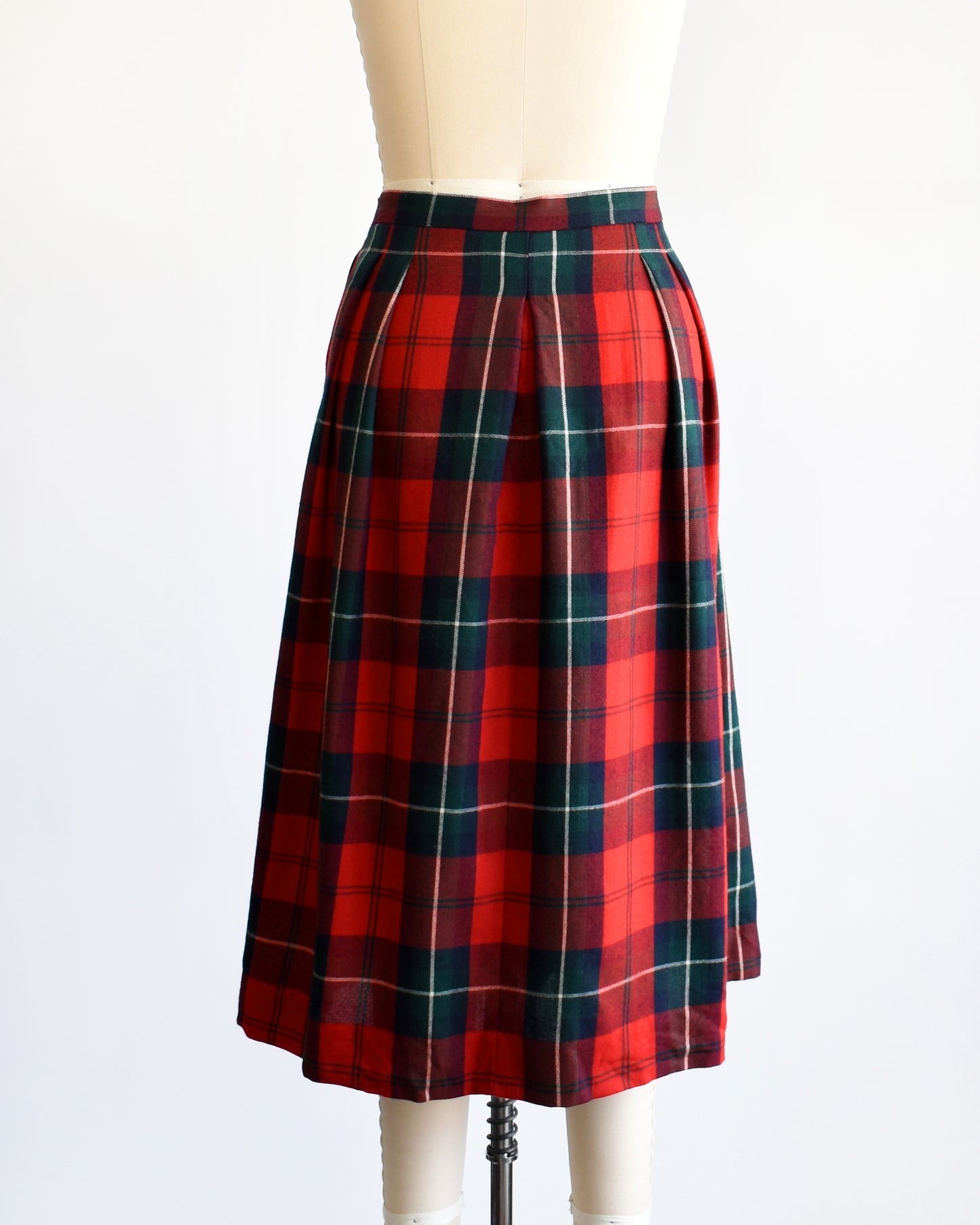 Back view of a vintage 80s red and green plaid pleated skirt on a dress form
