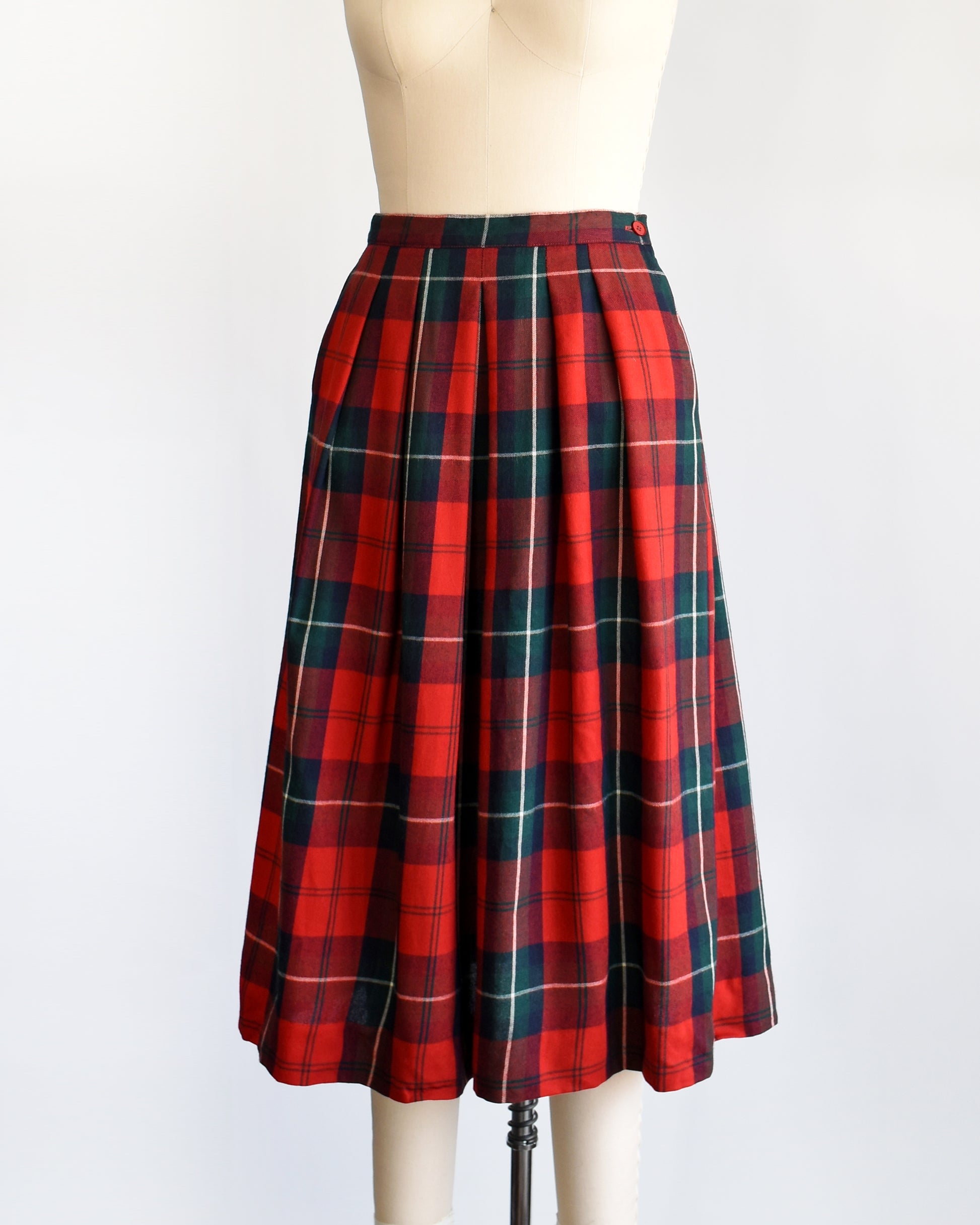 Side front view of a vintage 80s red and green plaid pleated skirt on a dress form