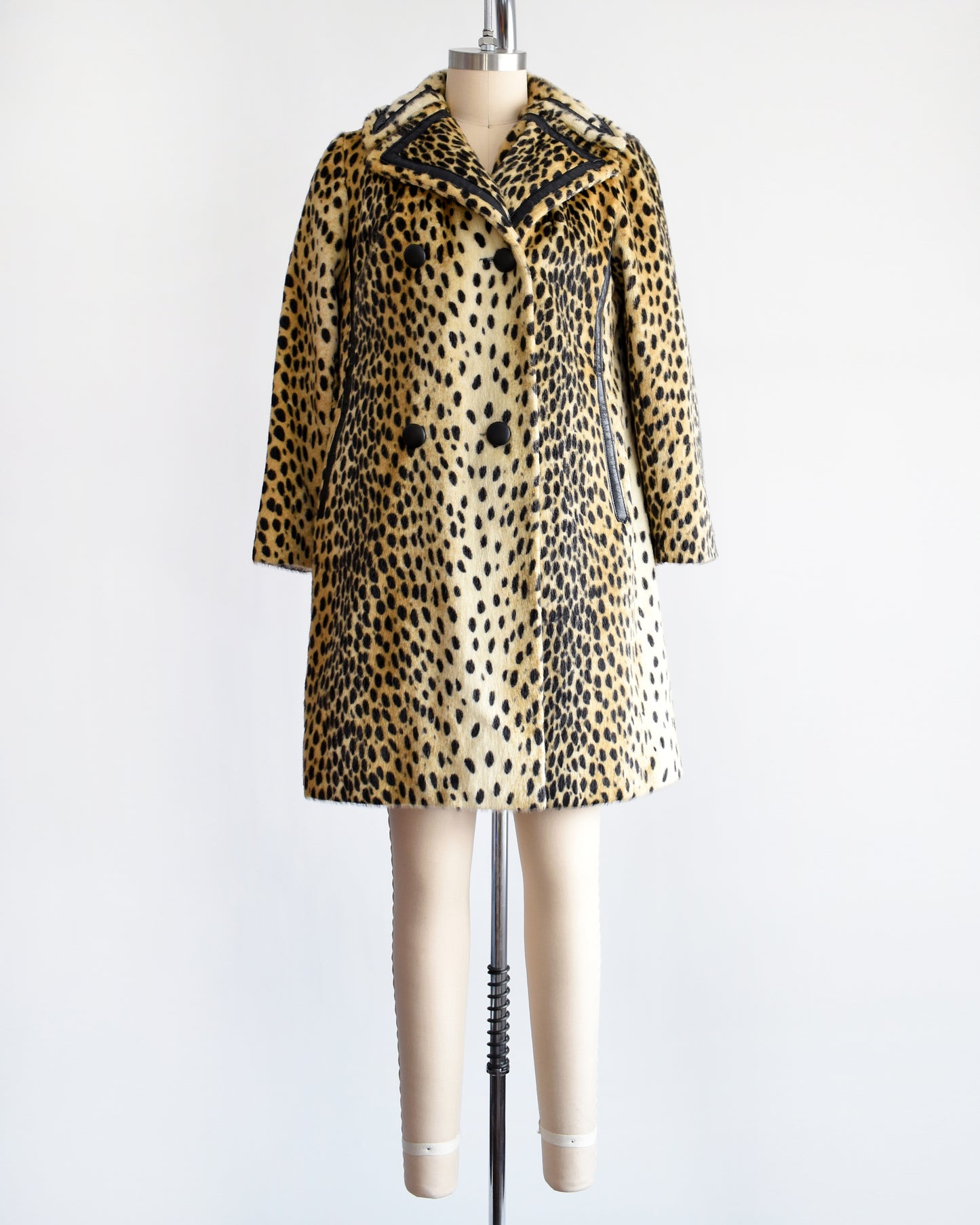 A faux fur cheetah print coat features golden faux fur with black spots and black faux leather trim