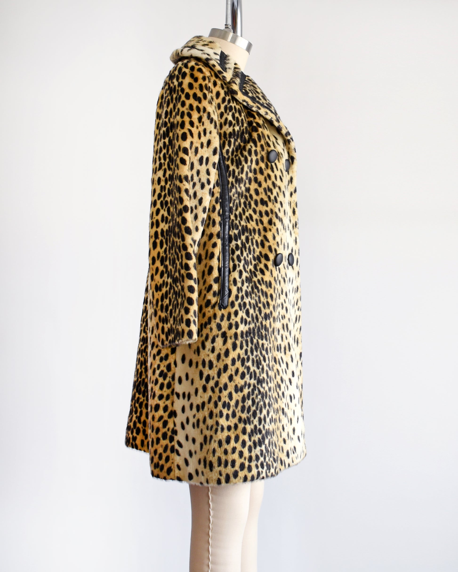 Side view of a faux fur cheetah print coat features golden faux fur with black spots and black faux leather trim