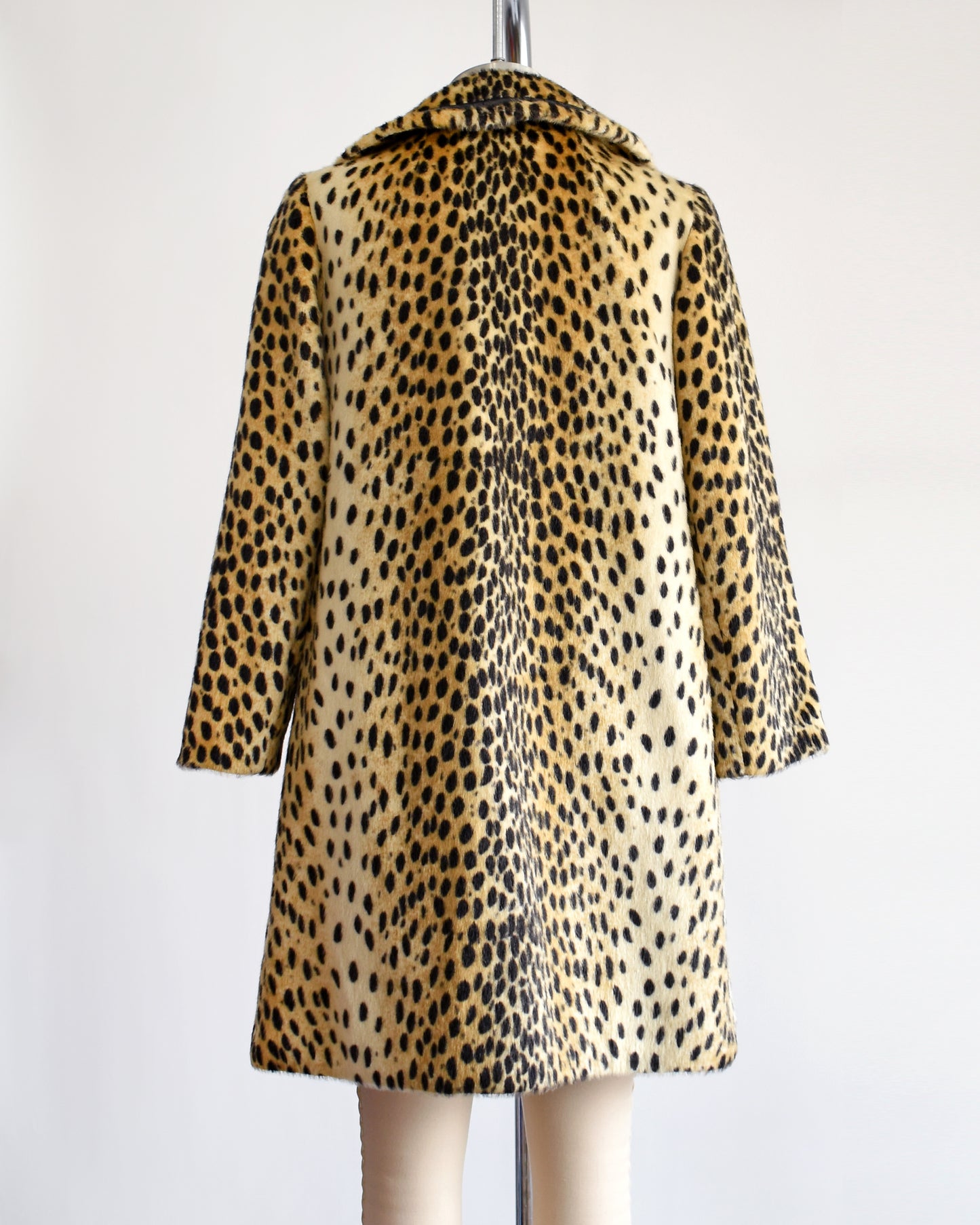 Back view of a faux fur cheetah print coat features golden faux fur with black spots and black faux leather trim
