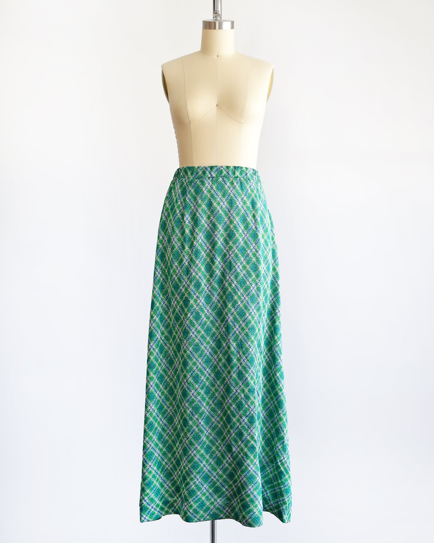 A vintage 1970s maxi skirt that features festive green, blue, and white plaid fabric with silver metallic threads.