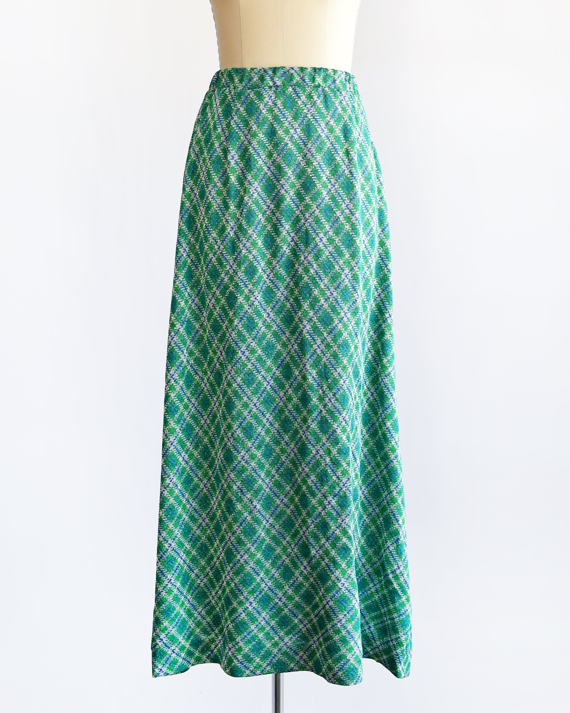 A vintage 1970s maxi skirt that features festive green, blue, and white plaid fabric with silver metallic threads.