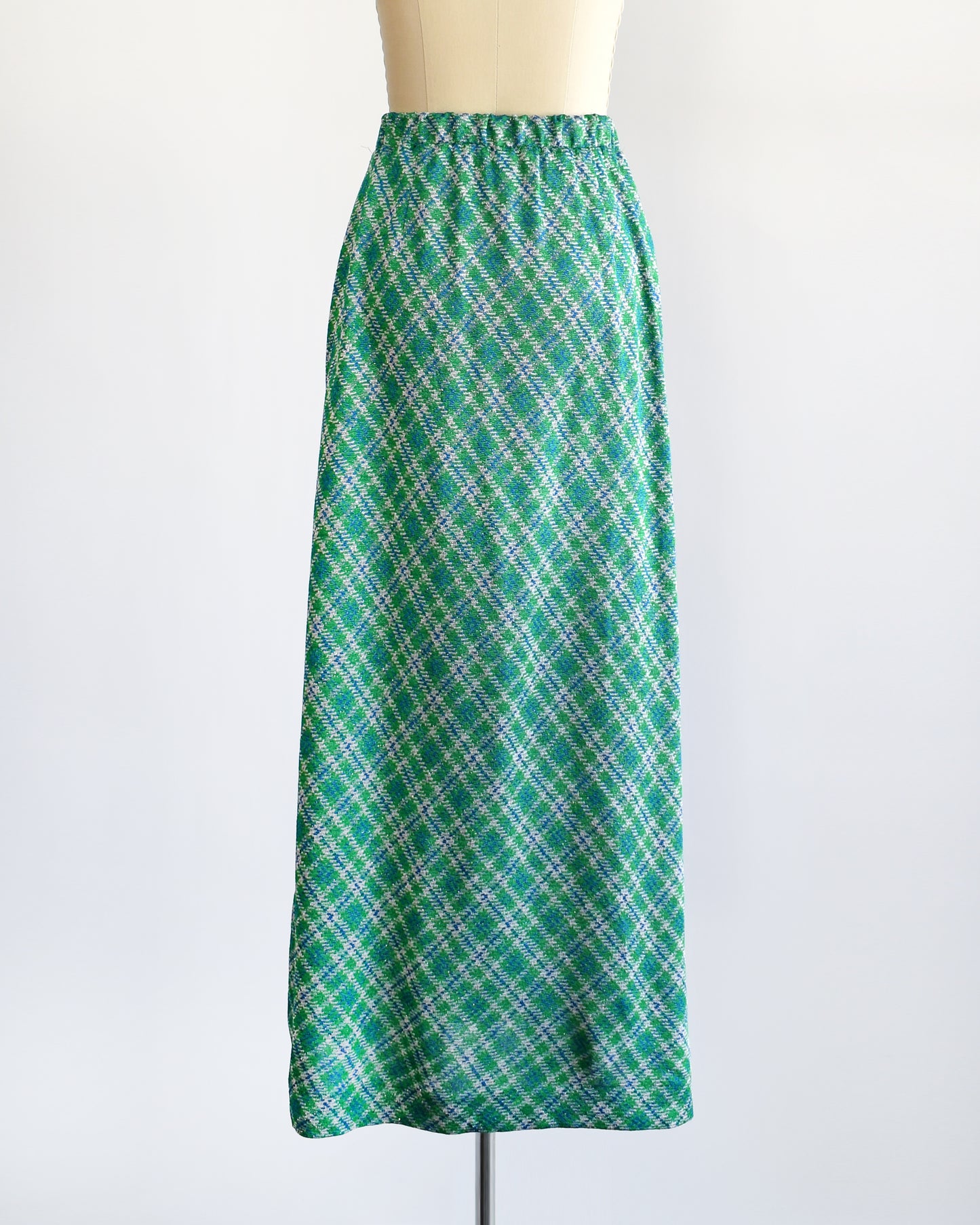 Back view of a vintage 1970s maxi skirt that features festive green, blue, and white plaid fabric with silver metallic threads.