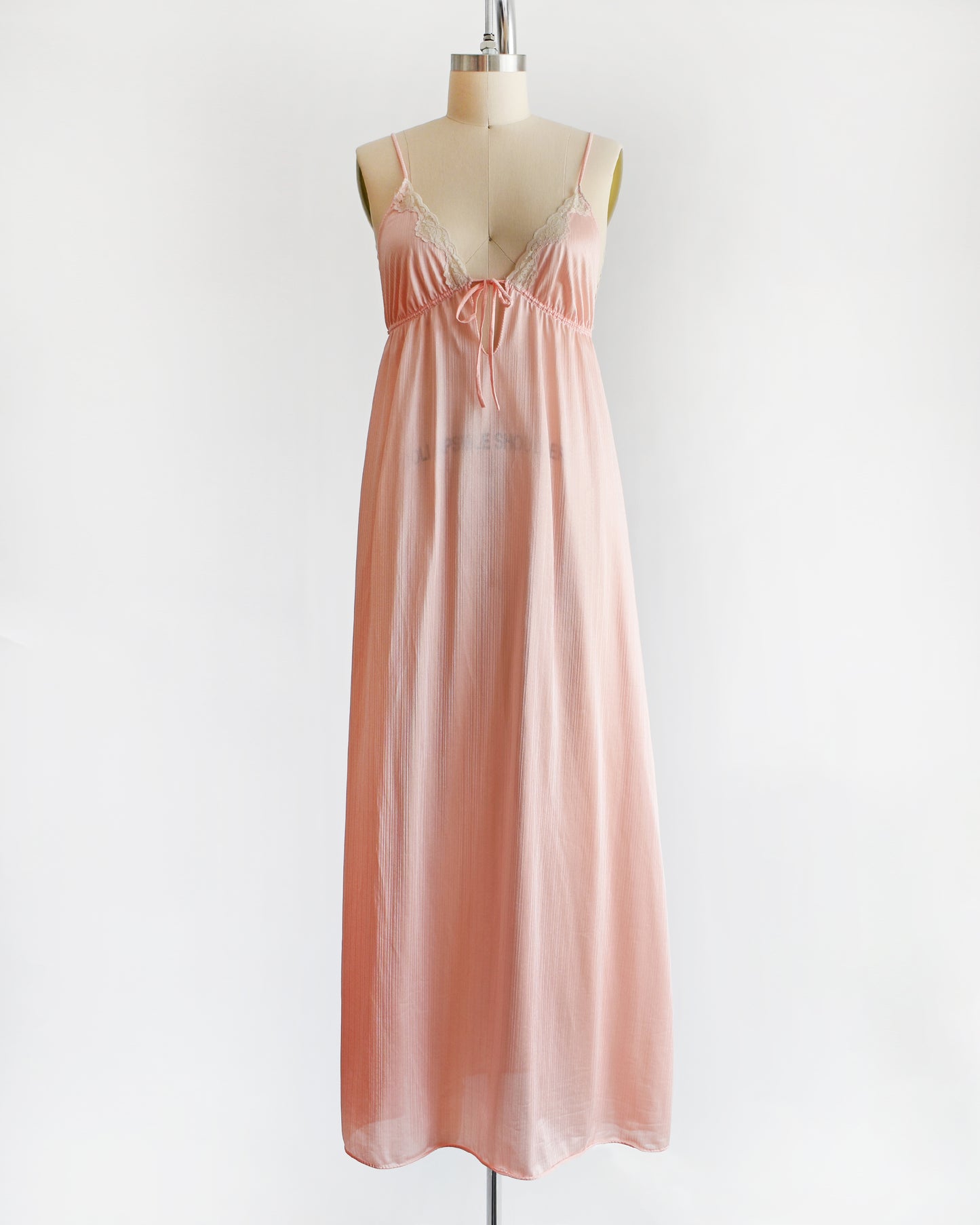 A vintage 1970s peachy pink nightgown that has lace trim on the bodice