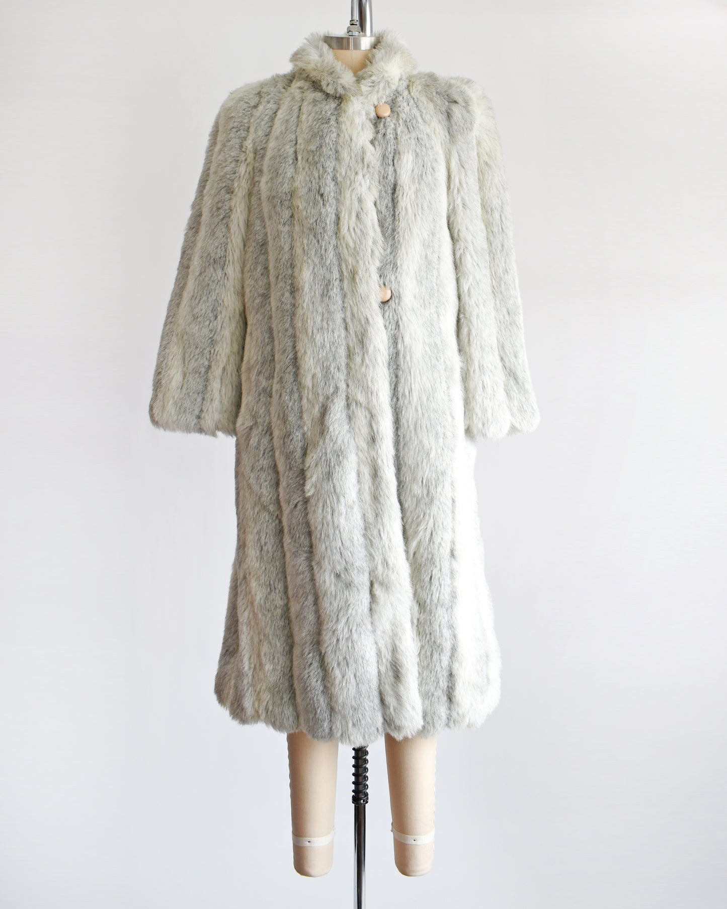 A vintage 1980s  cream colored faux fur coat with light and dark gray stripes. 